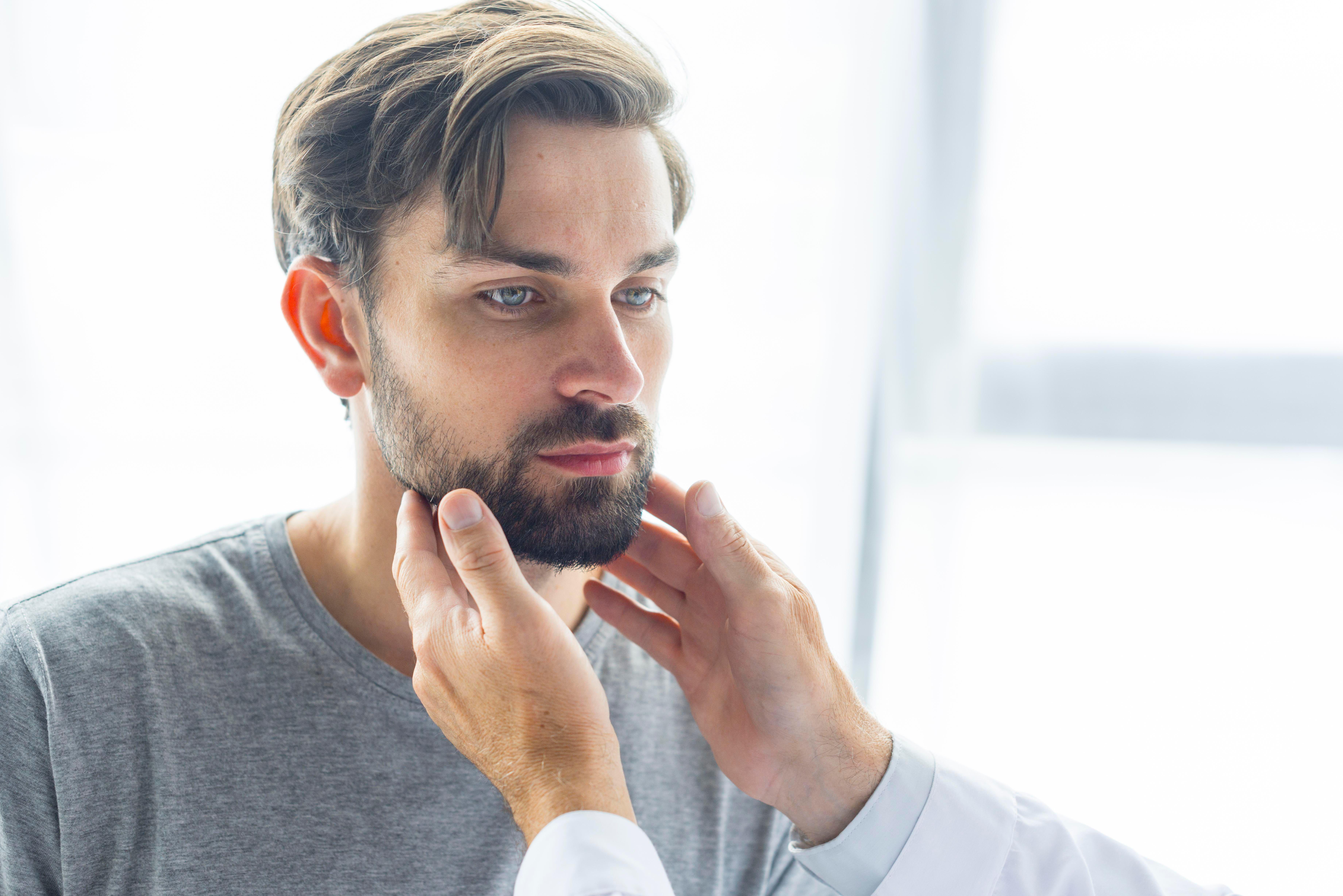 Doctor checking a young man's lymph nodes