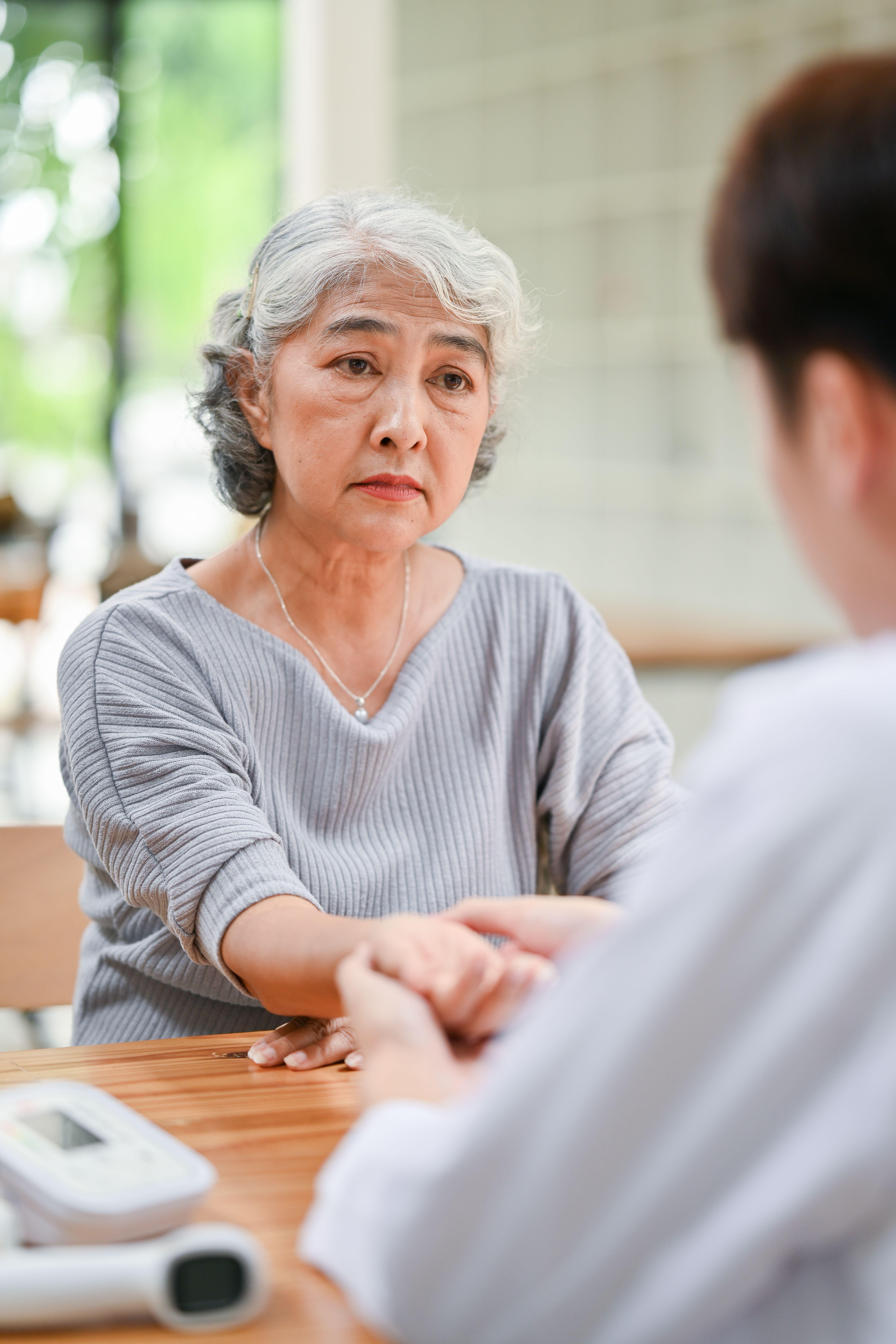 A concerned senior lady being diagnosed and checked for pulse on her wrist by a doctor during her medical checkup at a hospital