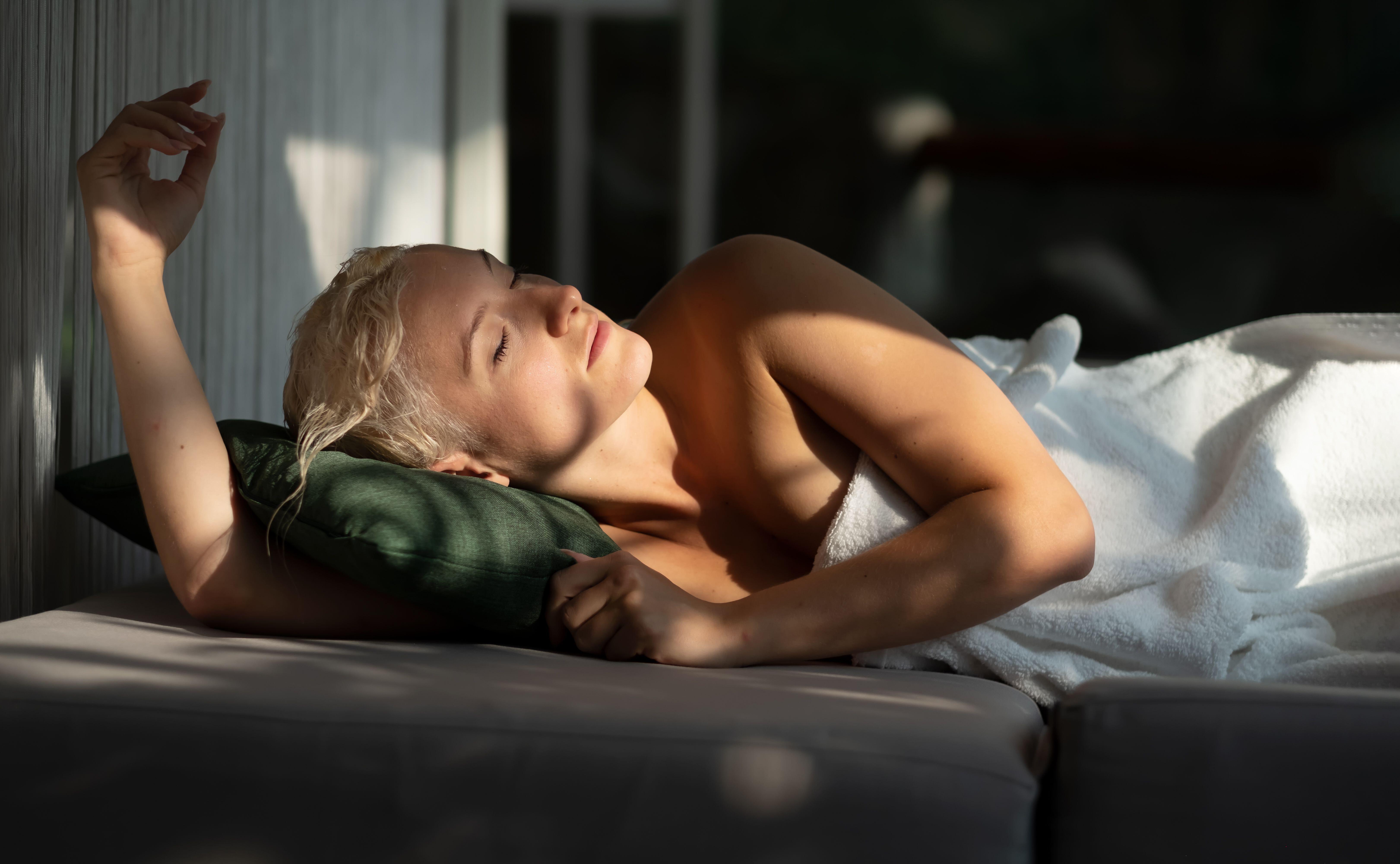 Woman lies on bed in towel with wet hair