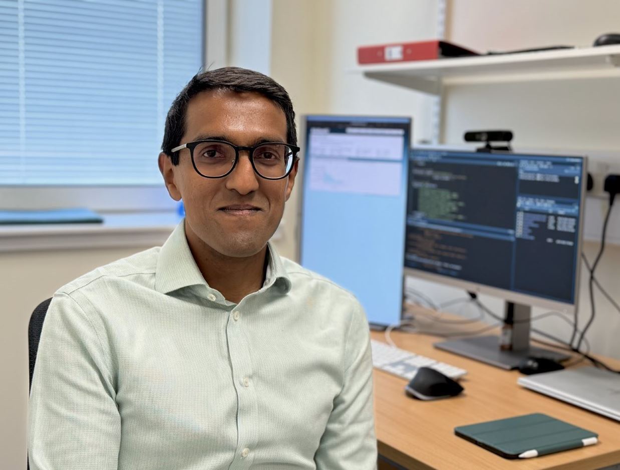 Dr Dhan Senaratne in shirt, sitting at a desk