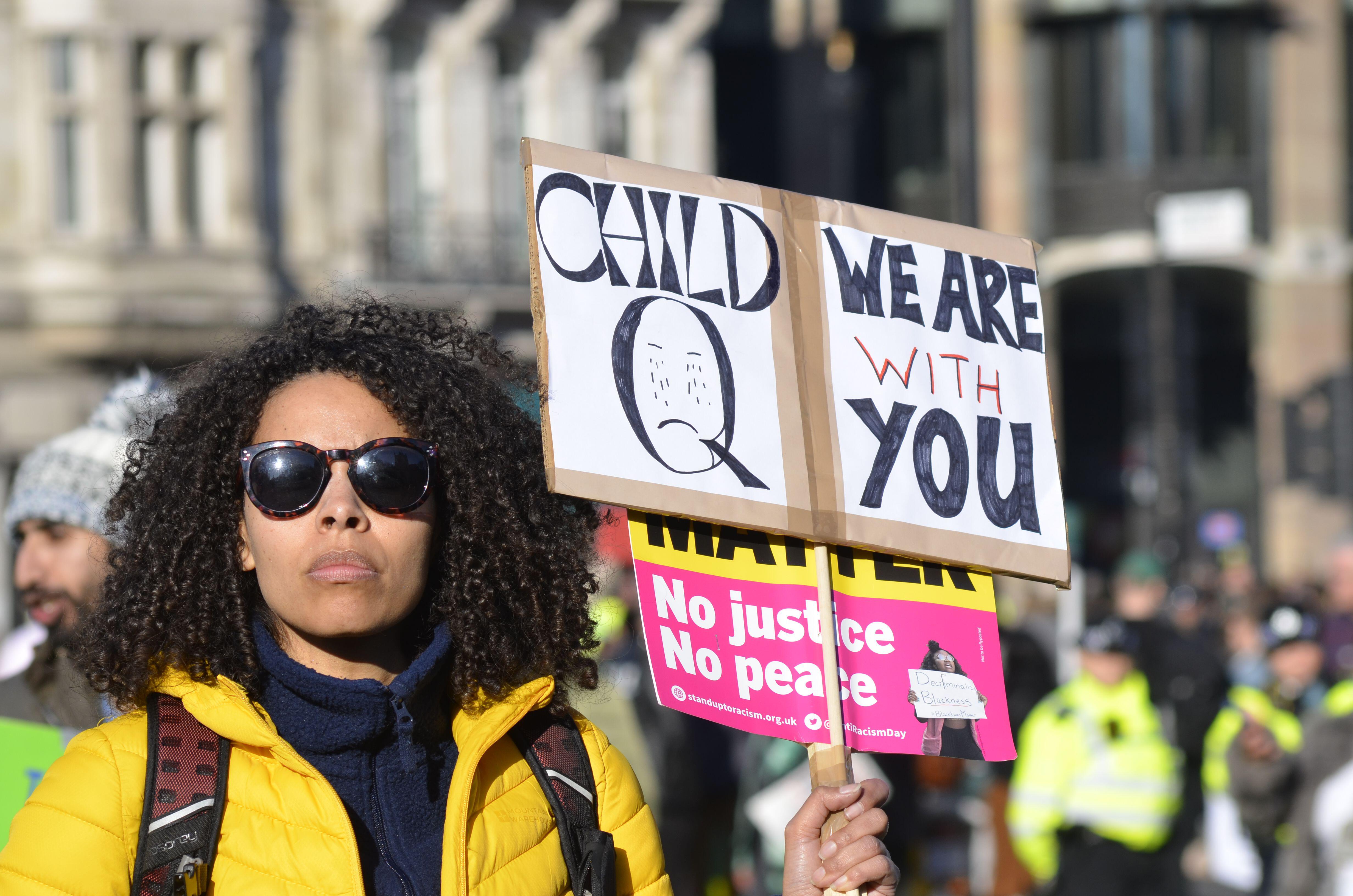 Woman holds Child Q sign at protest