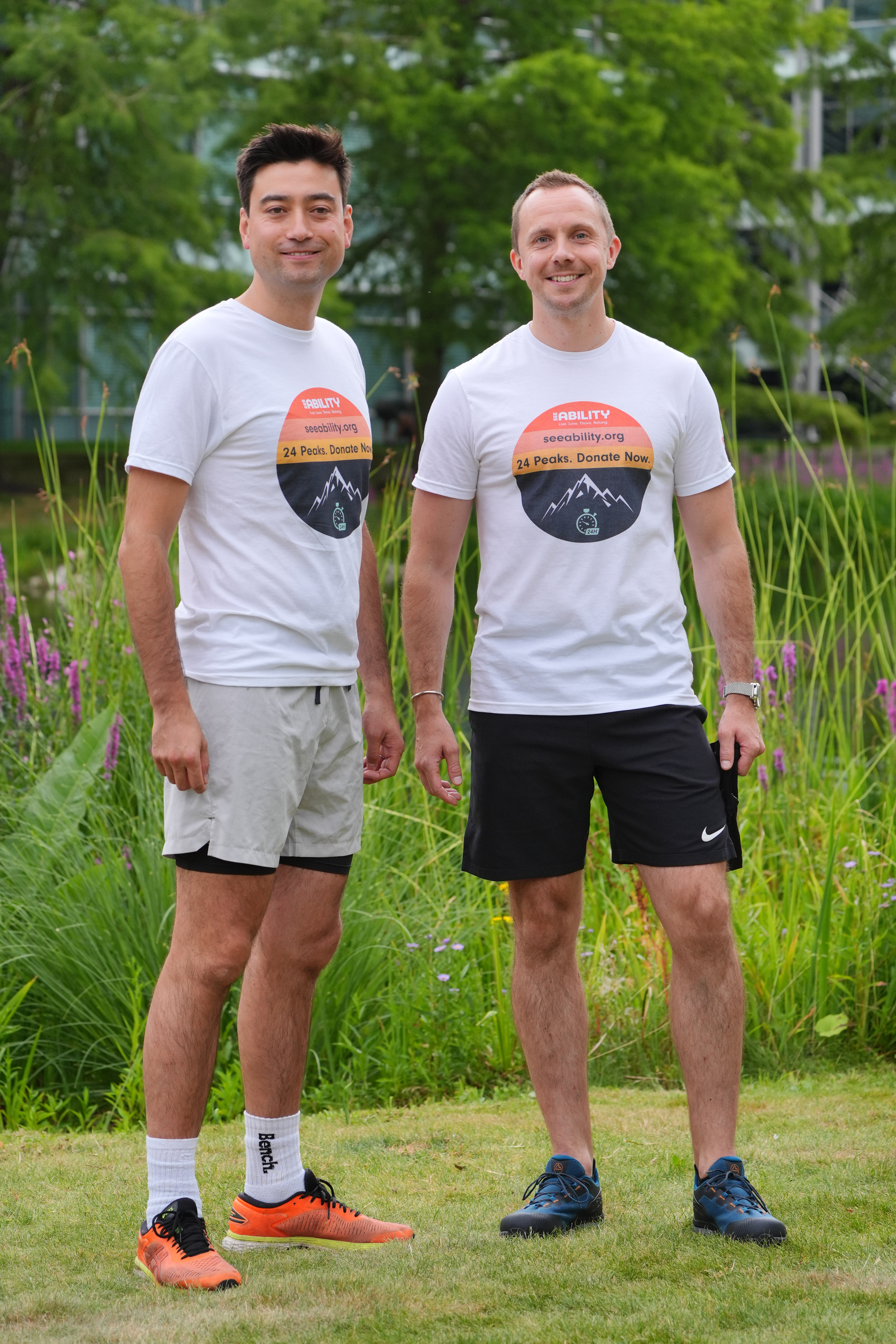 Two men smiling while standing in a park