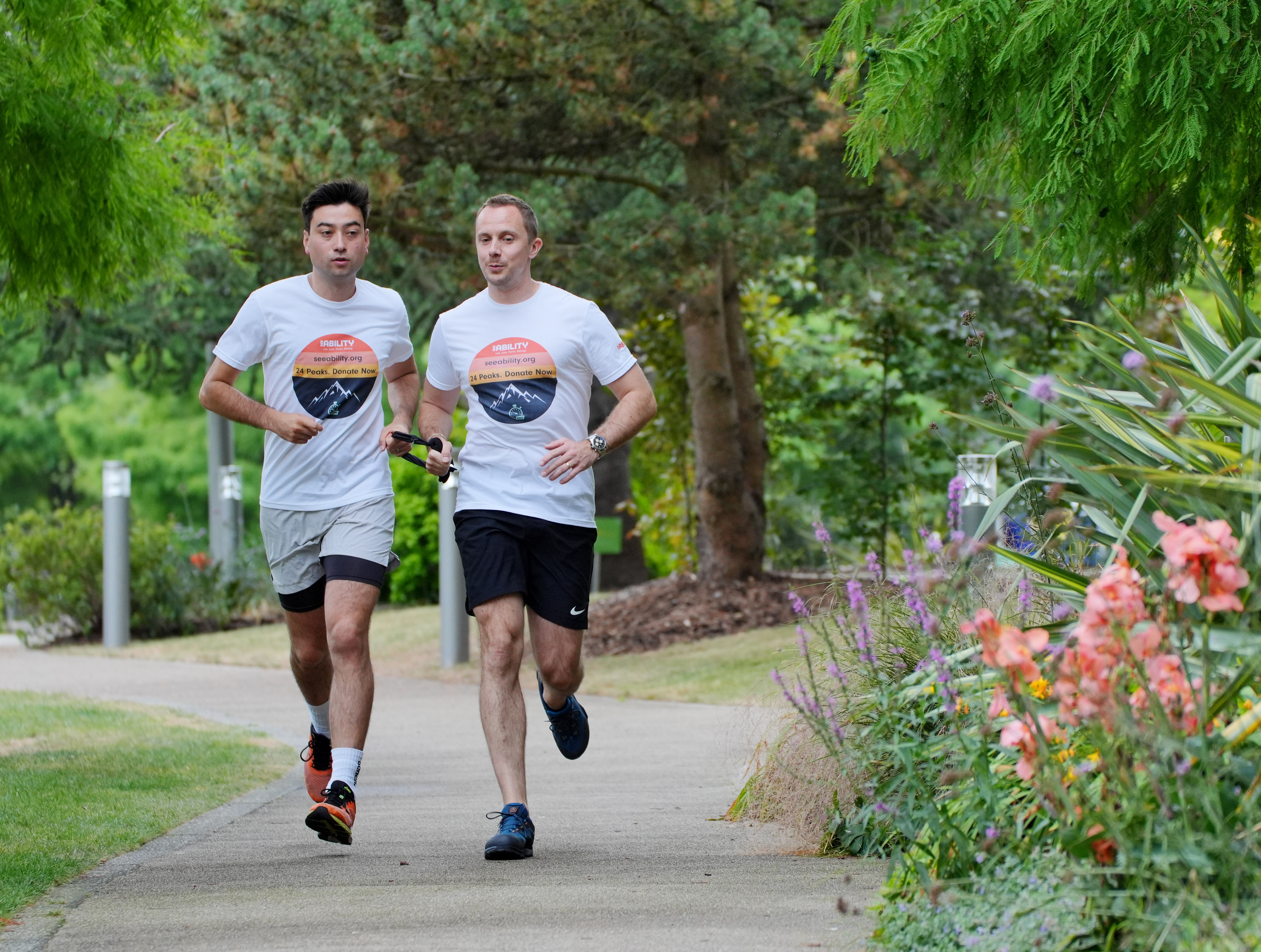 Wide shot of two men running together while tethered with a black strap