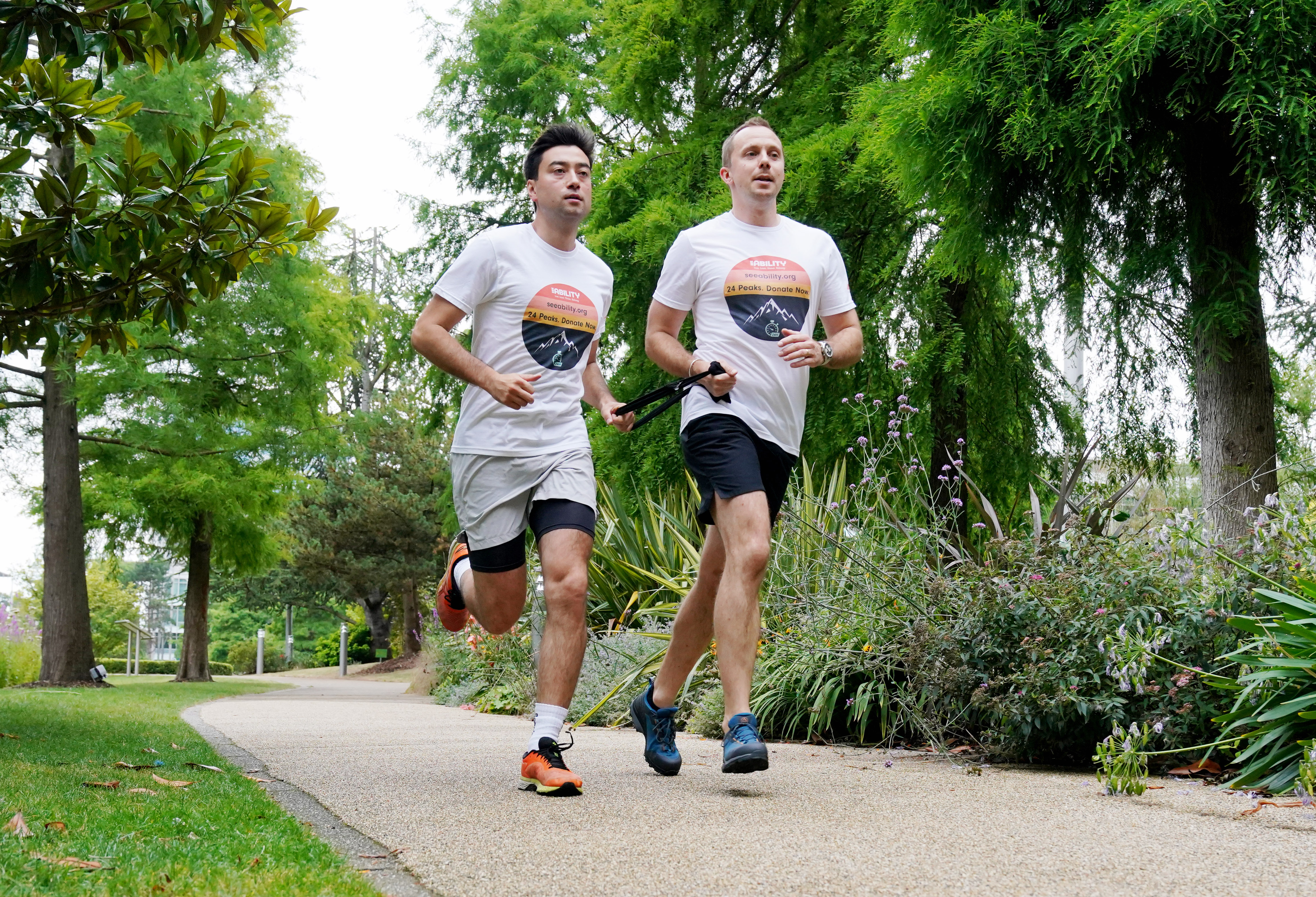 Two men running through a park while tethered together with a black strap