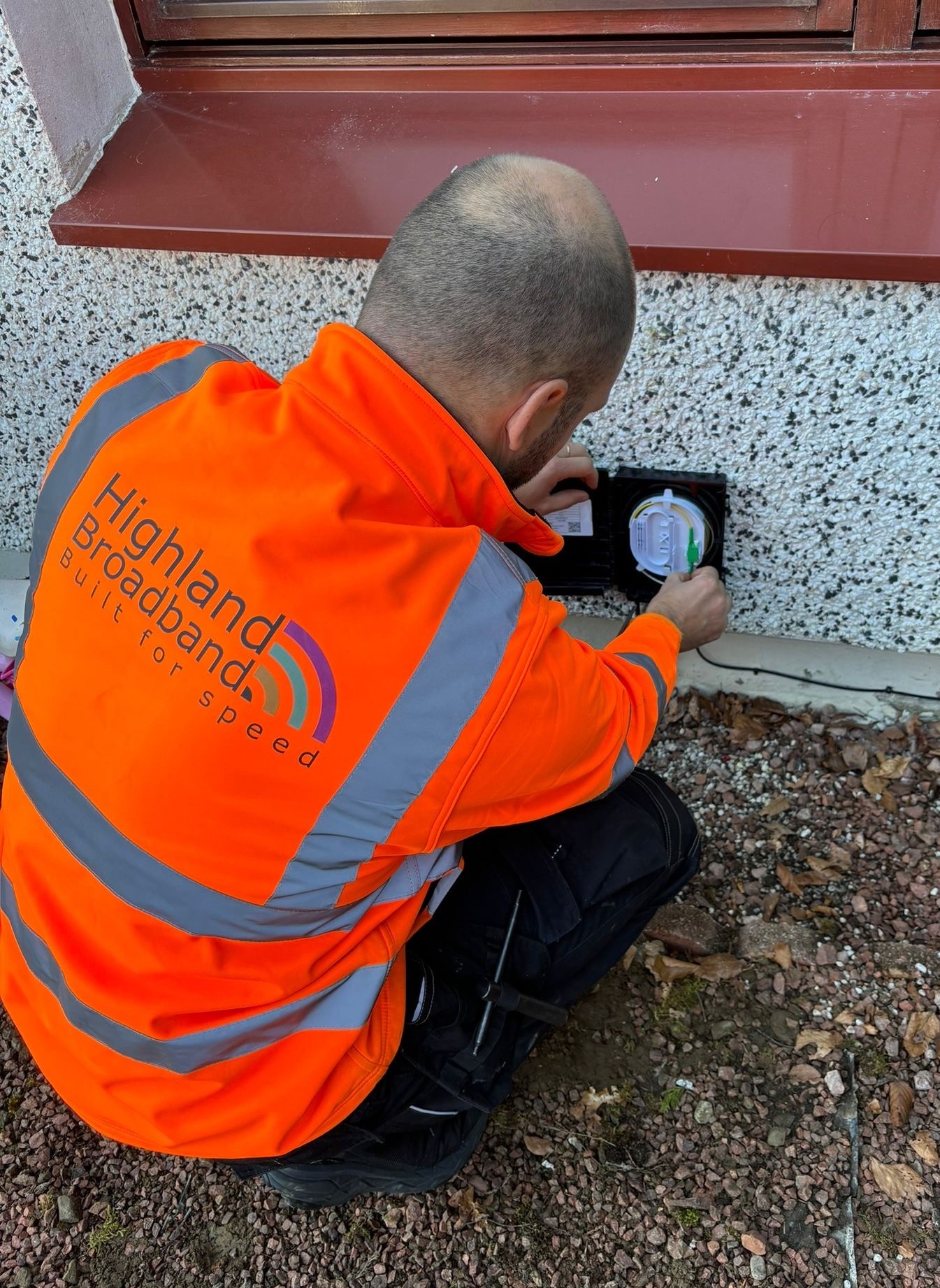 Highland Broadband engineer installing equipment on the side of a building