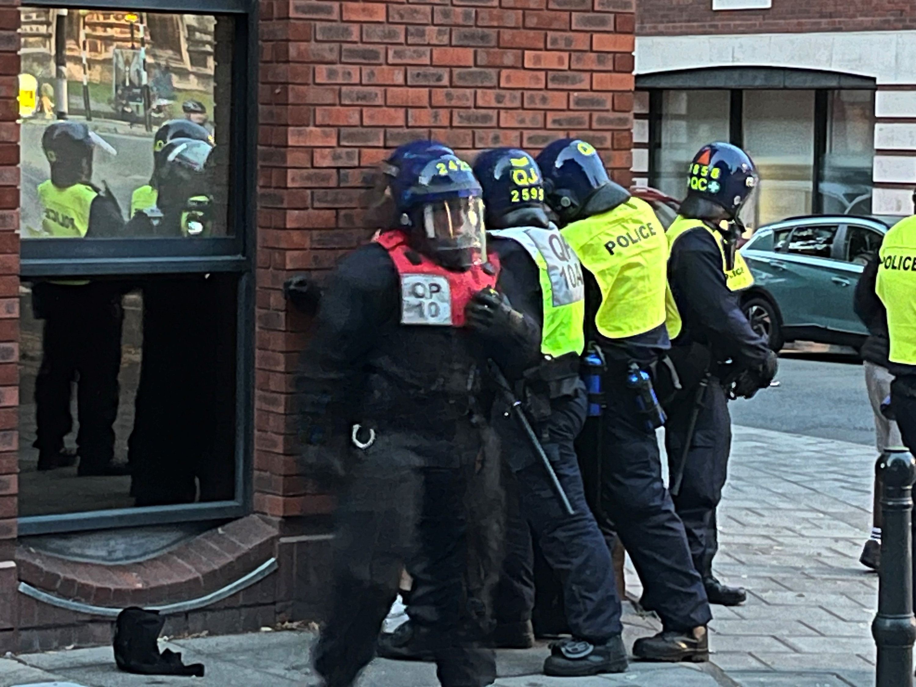 A group of police officers in protective gear on a street corner