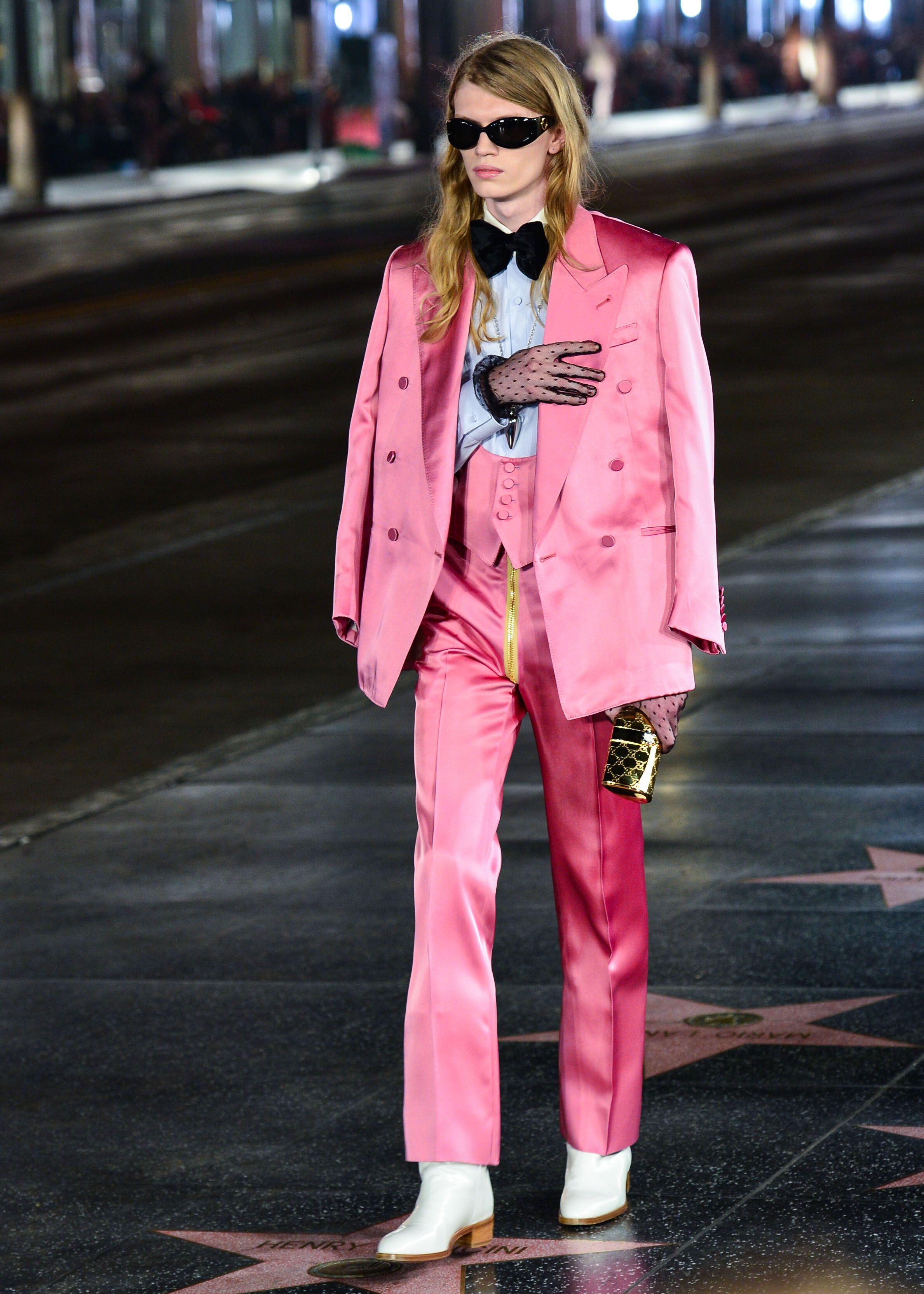 Model walks down street in pink silk Gucci double breasted suit