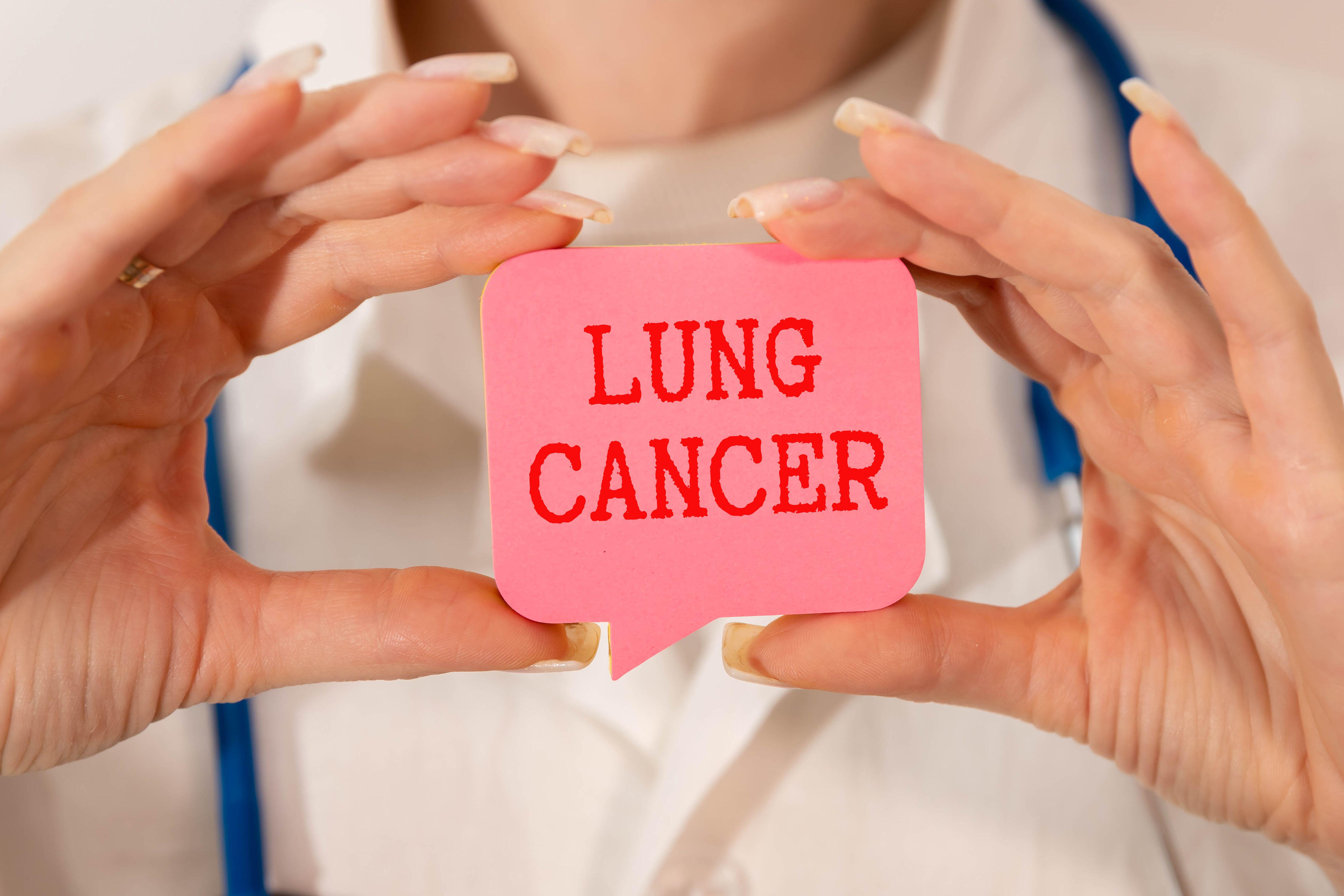 Close-up of a man holding a pink sign which says lung cancer on it