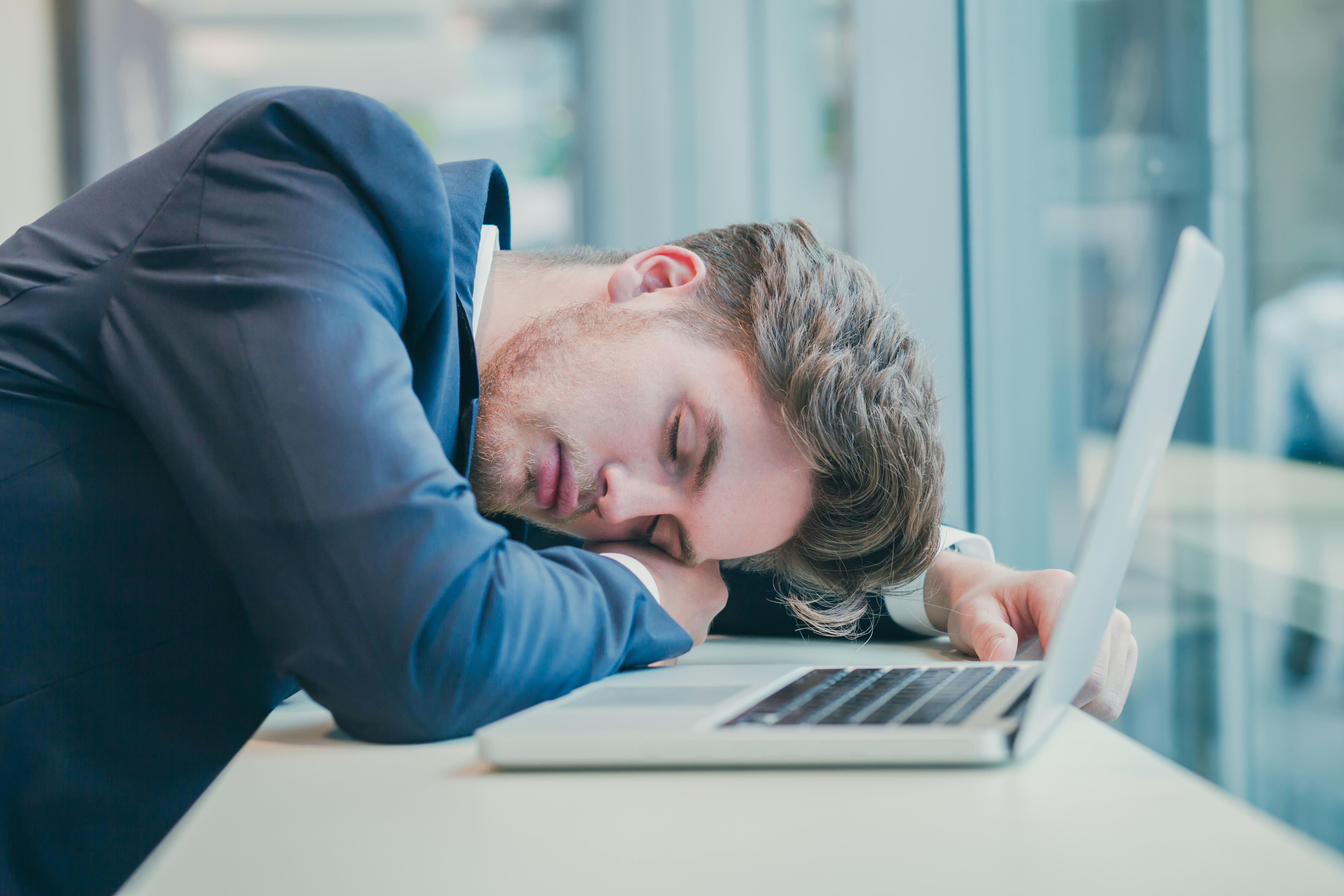 Tired businessman sleeping on his desk next to his computer