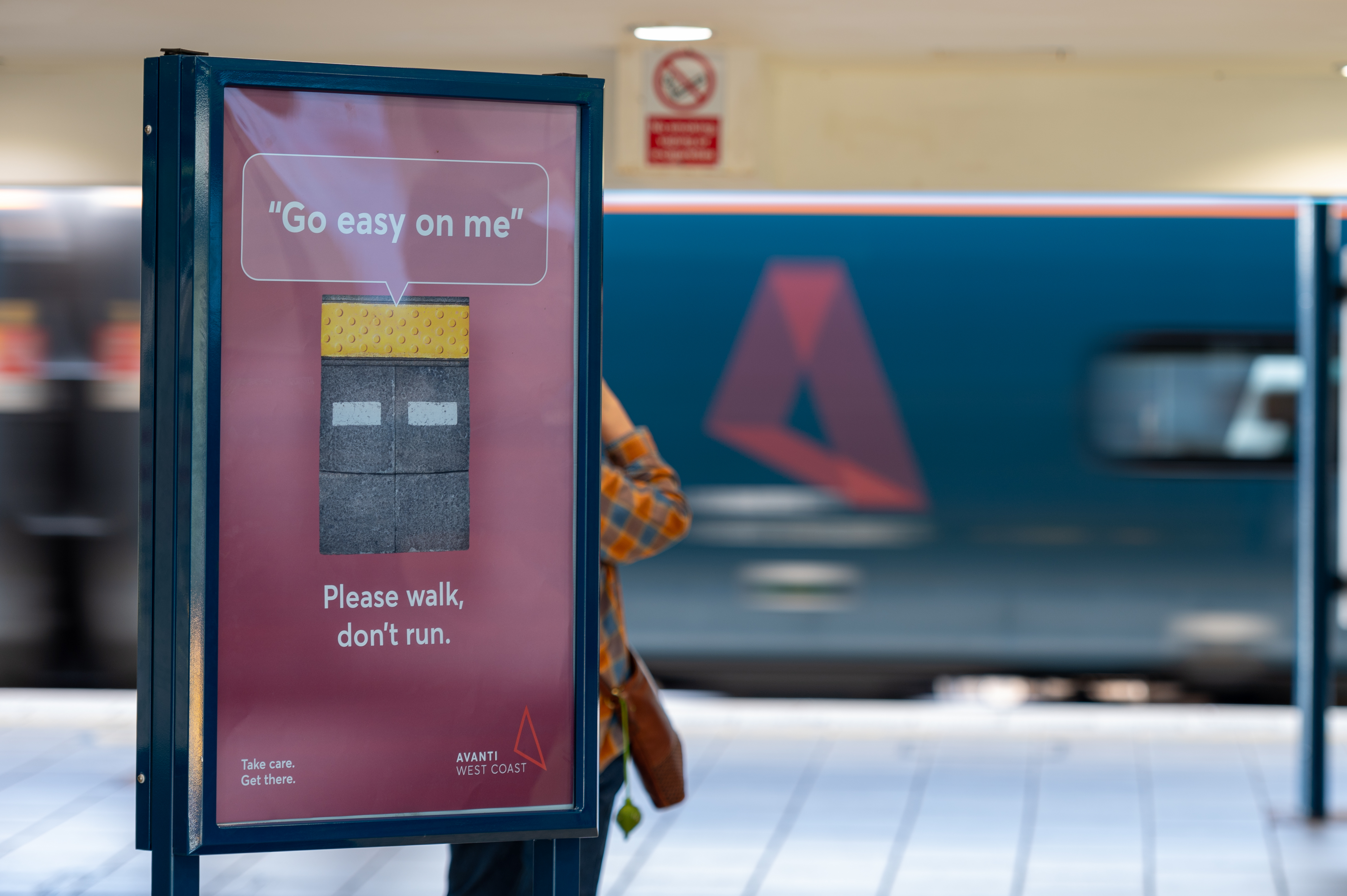 An advert showing a railway station platform edge with a speech bubble coming from it saying 'Go easy on me'