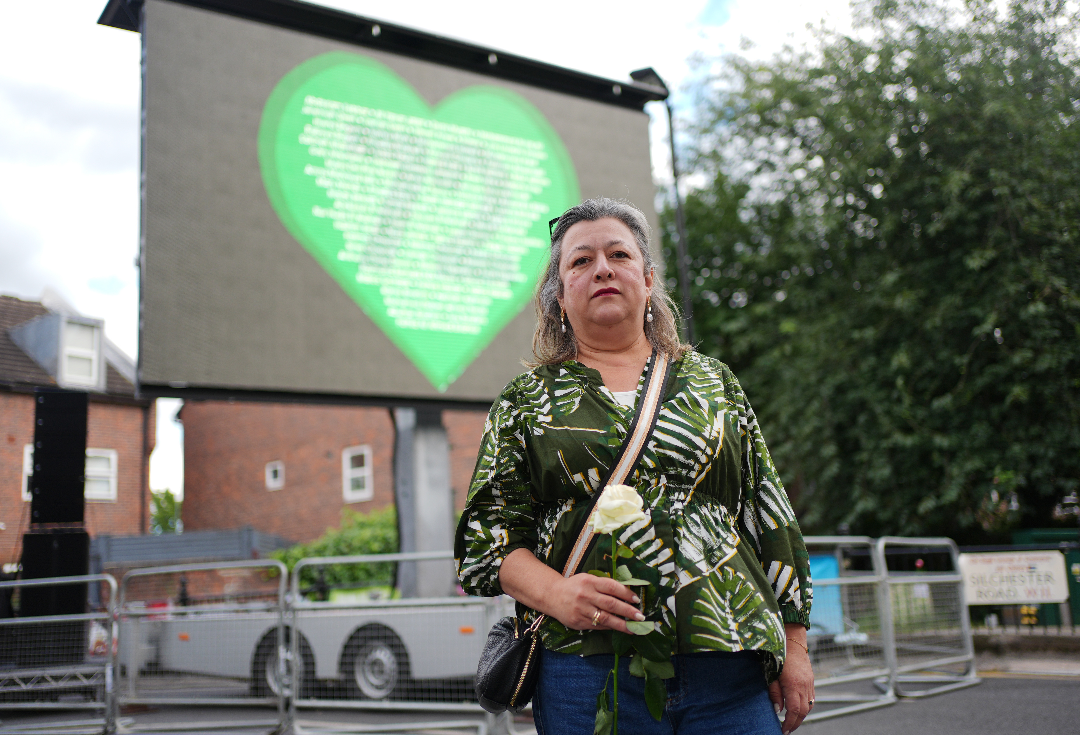 Bereaved family member Sandra Ruiz stands in front of a green heart in memory of the Grenfell Tower victims 