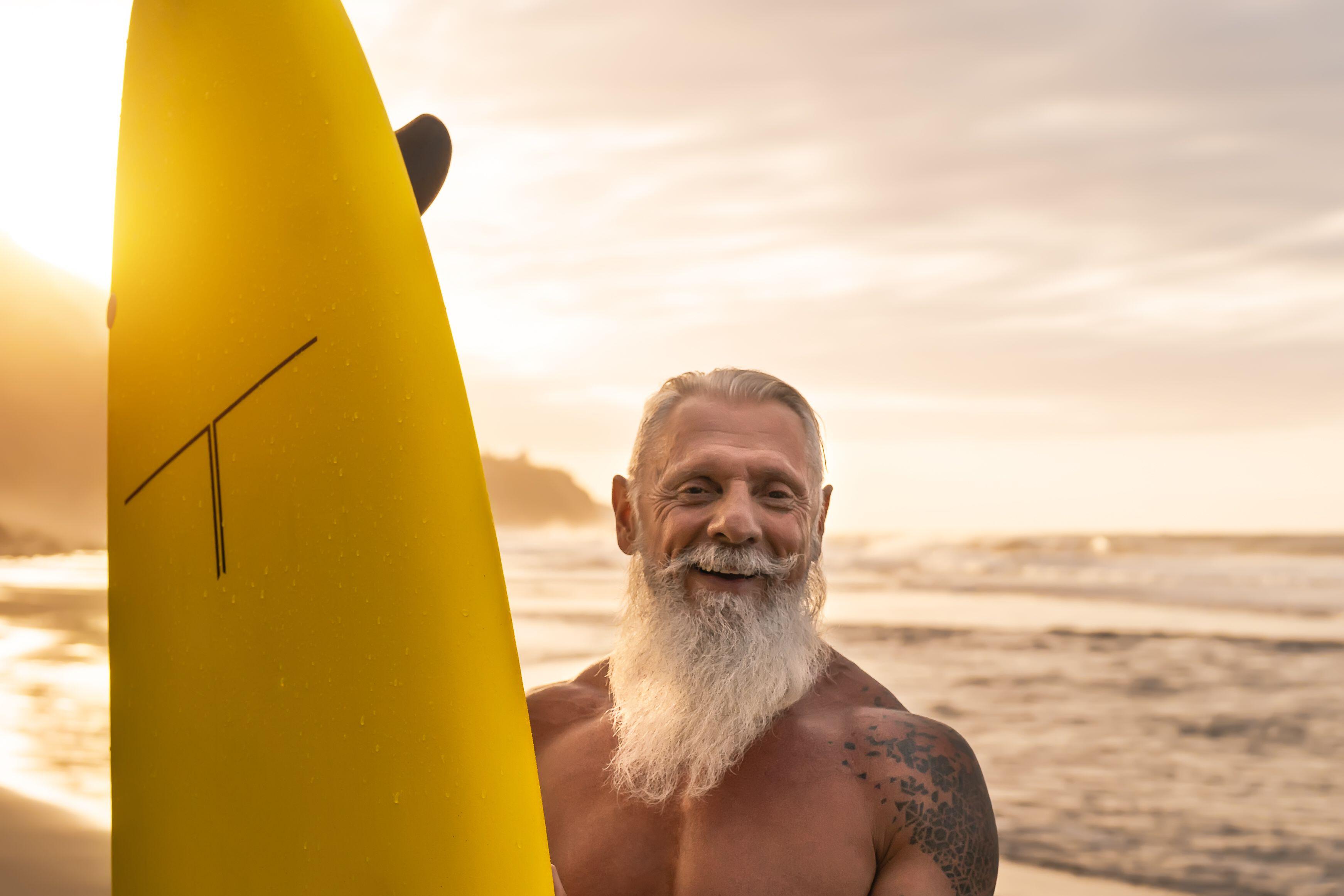 Happy bearded senior man having fun surfing during sunset 