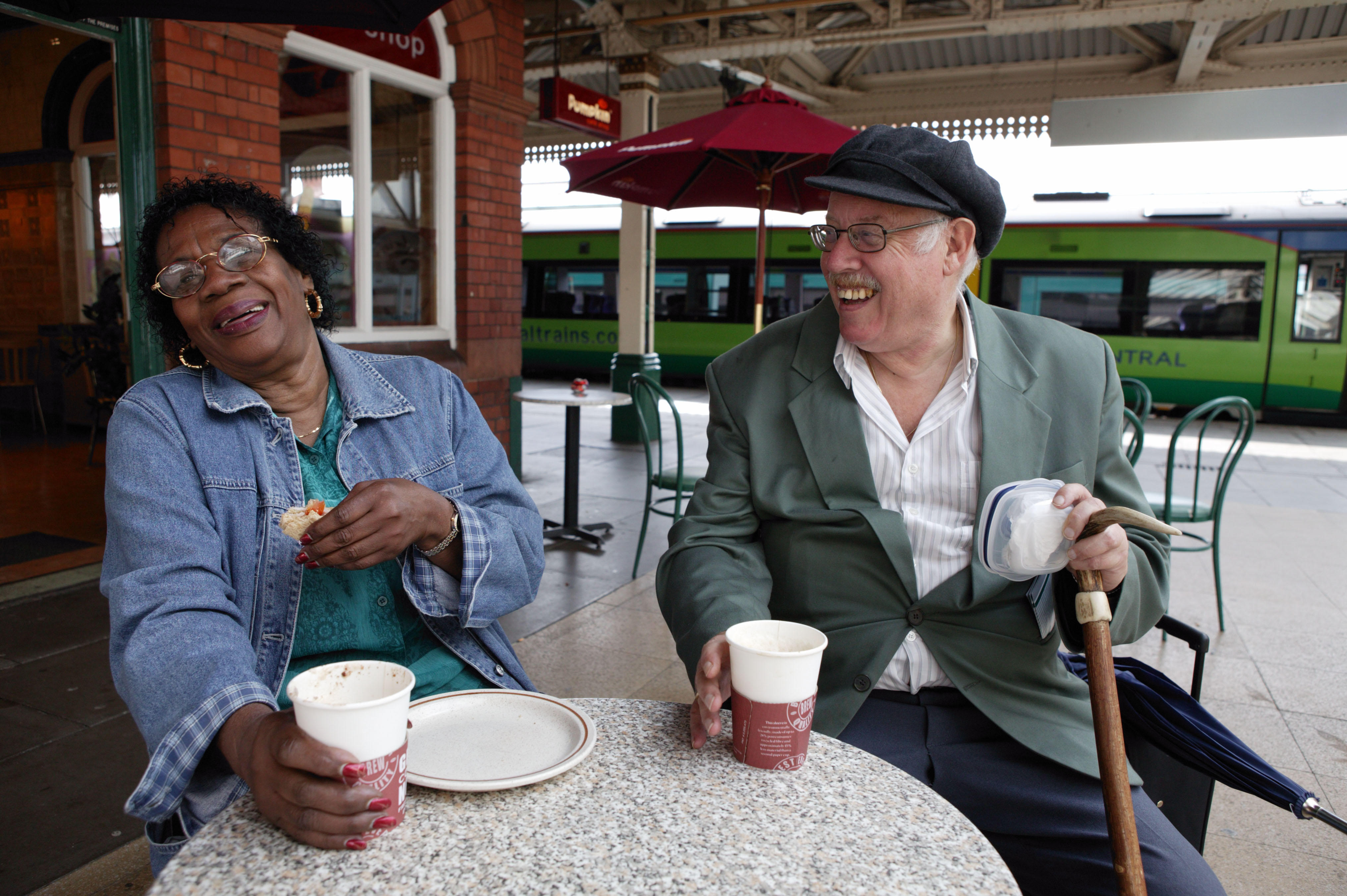 Elderly couple laughing in a cafe at train station