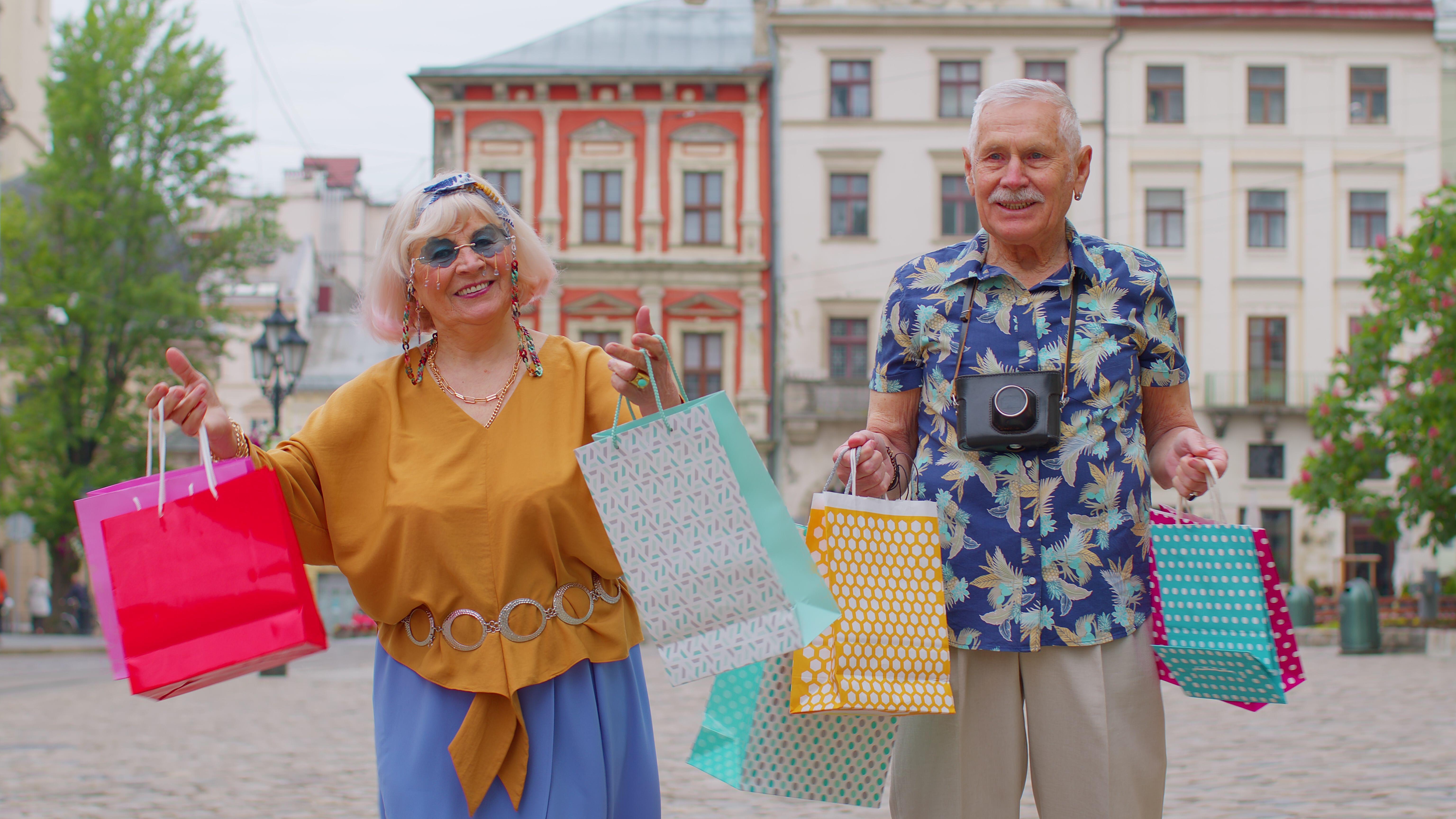  Elderly stylish man and woman on holiday holding colourful shopping bags