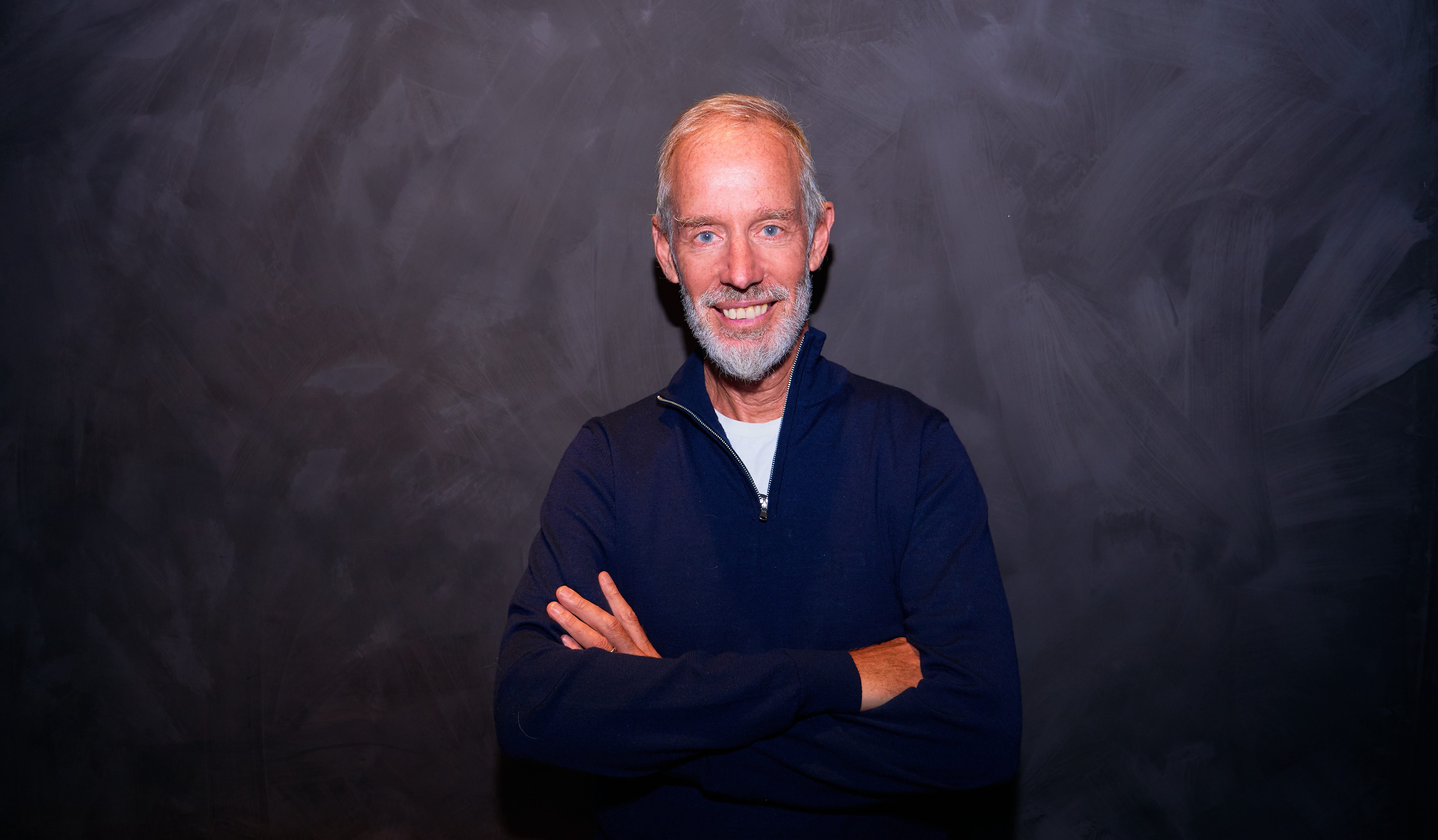 Parkrun founder Paul Sinton-Hewitt smiling and with his arms folded