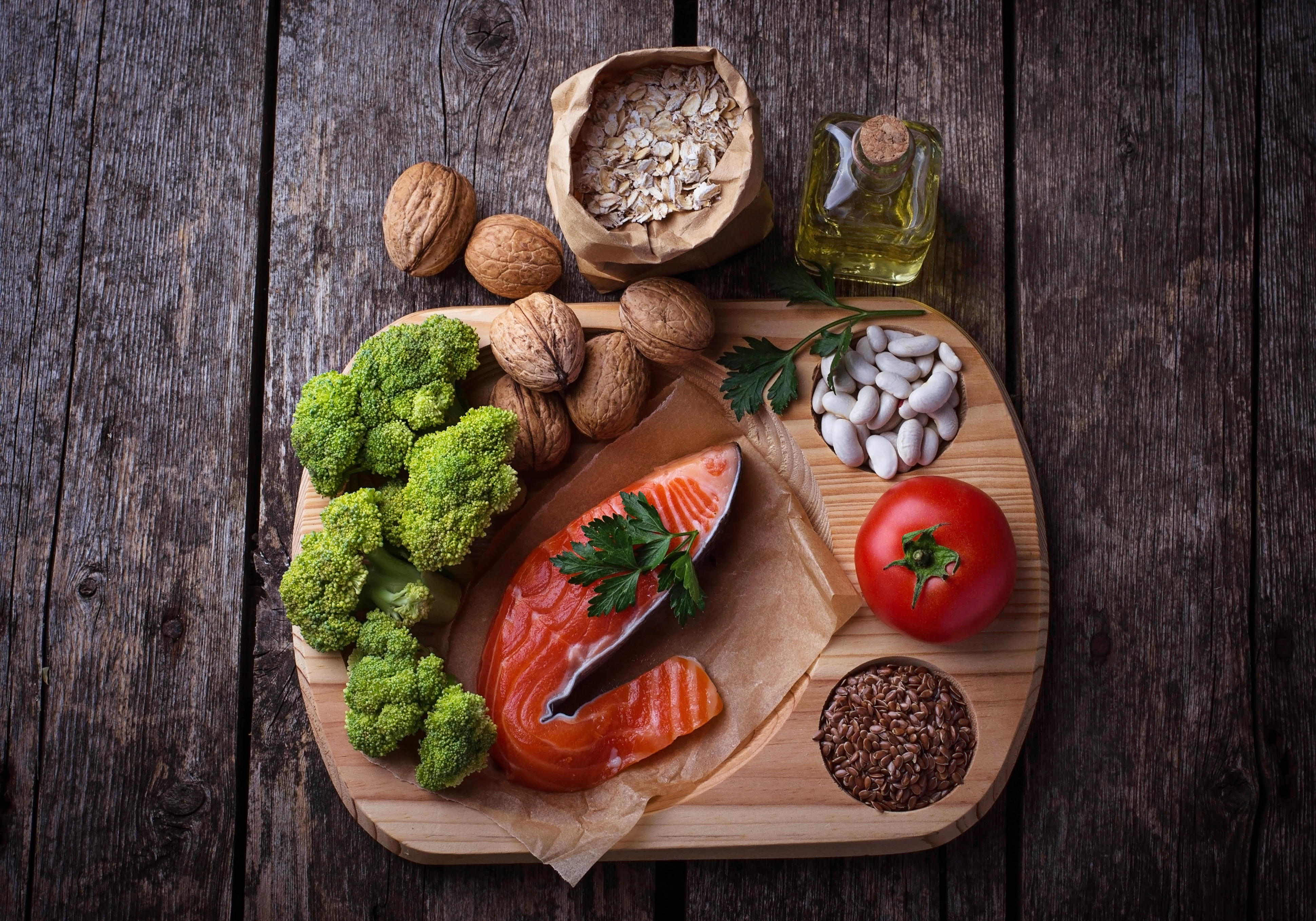 Photo of ingredients that help lower cholesterol diet and are good for the heart including salmon, broccoli, nuts, seeds 