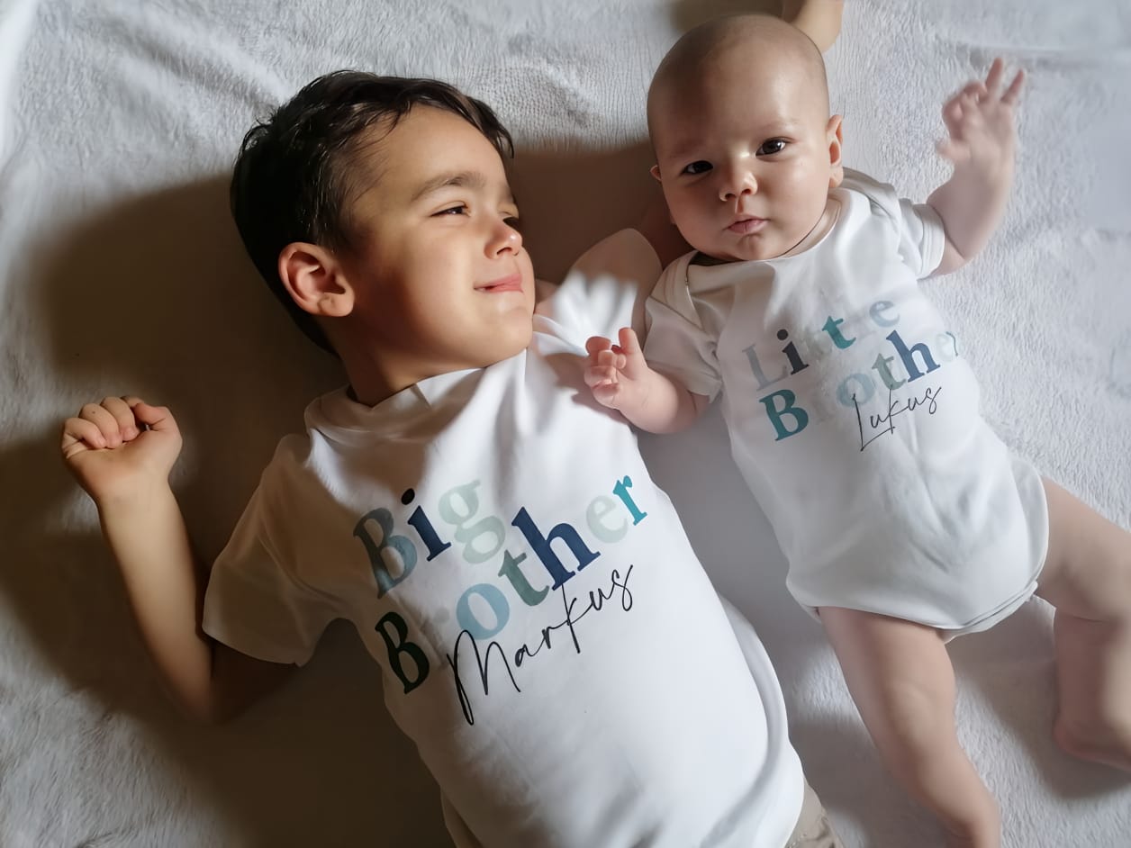 A boy and a baby lying on a bed