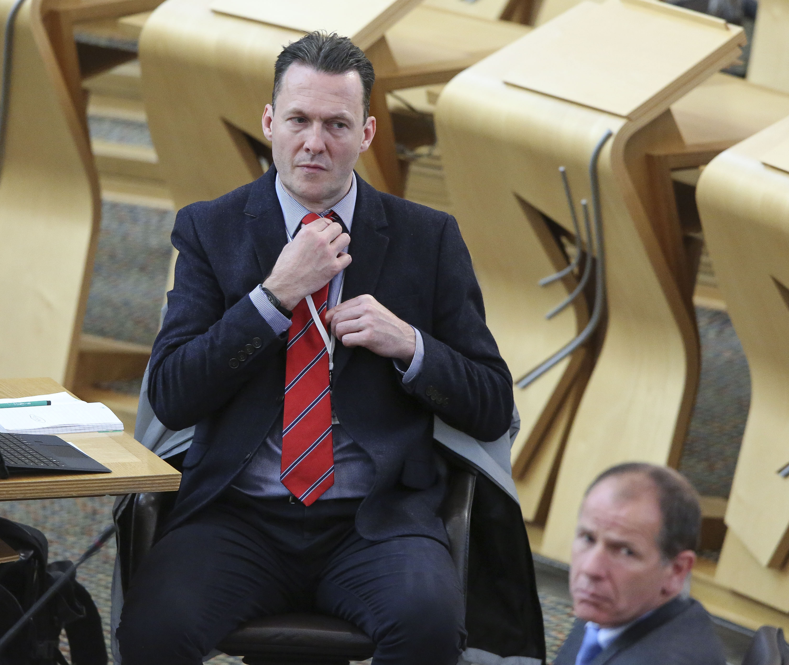 MSP Russell Findlay adjusts his tie during a debate in the Scottish Parliament