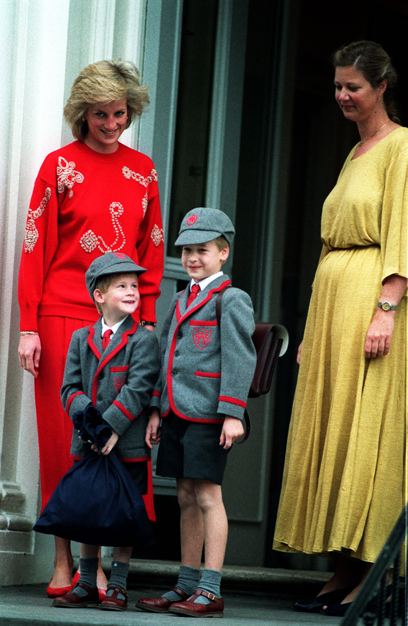 Harry, in school uniform, looks up at William on his first day at school as Diana looks proudly on