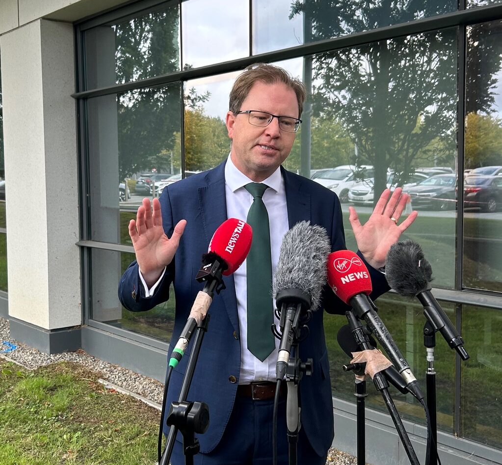 James Lawless gestures as he speaks into a number of microphones