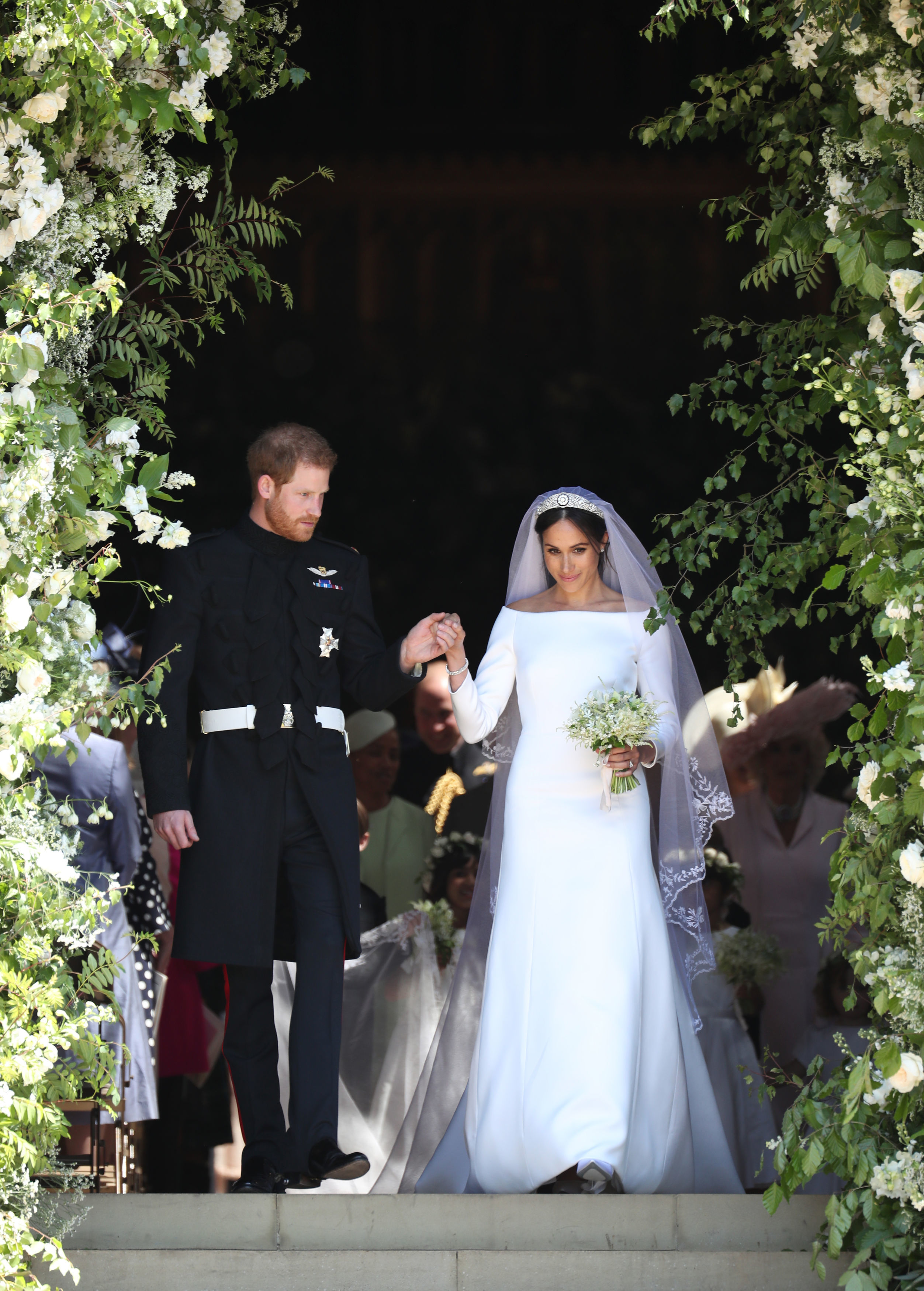 Groom Harry, 33 holds bride Meghan's hand as they leave the flower adorned St George's Chapel on their wedding day