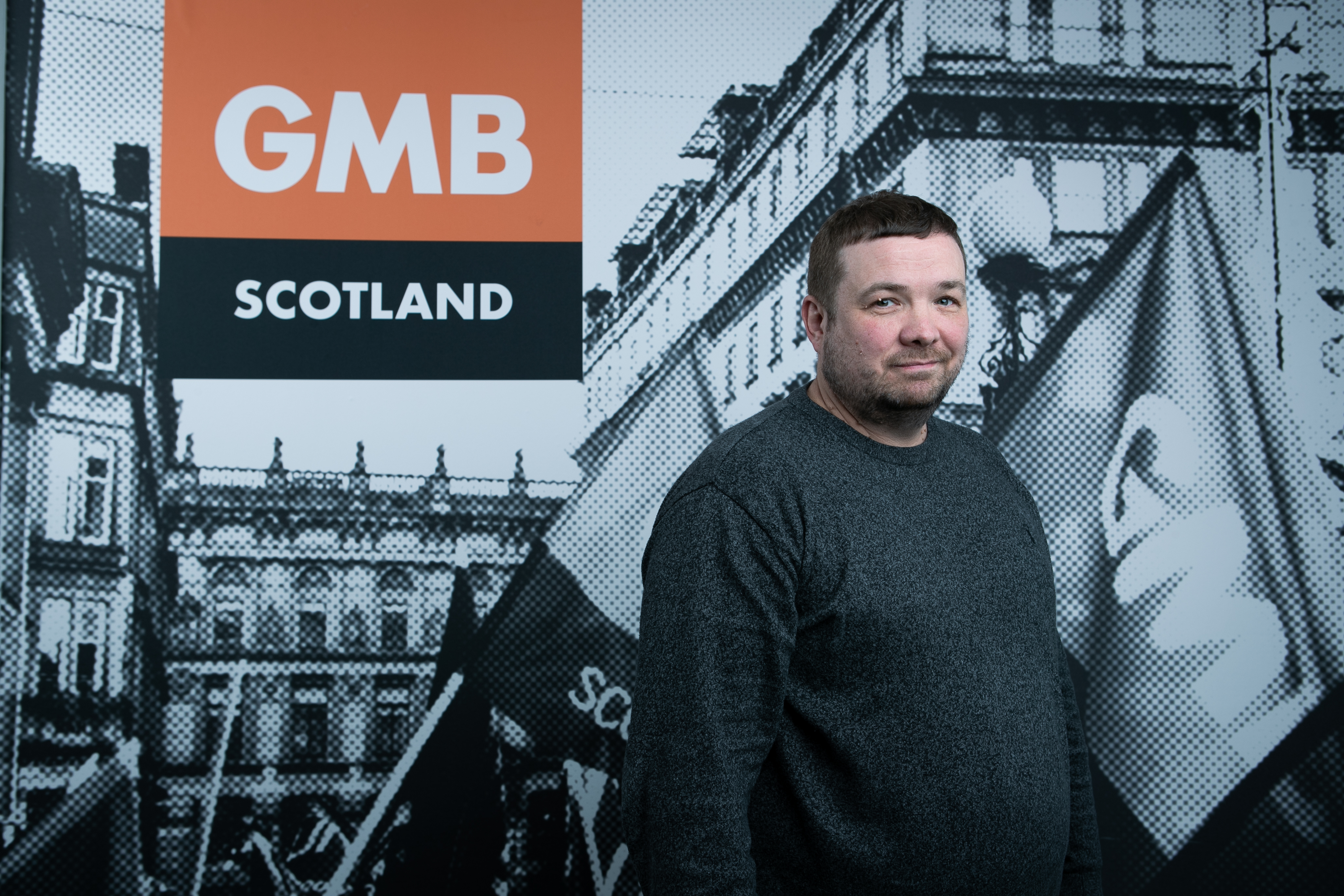 Robert Deavy standing in front of a GMB Scotland backdrop