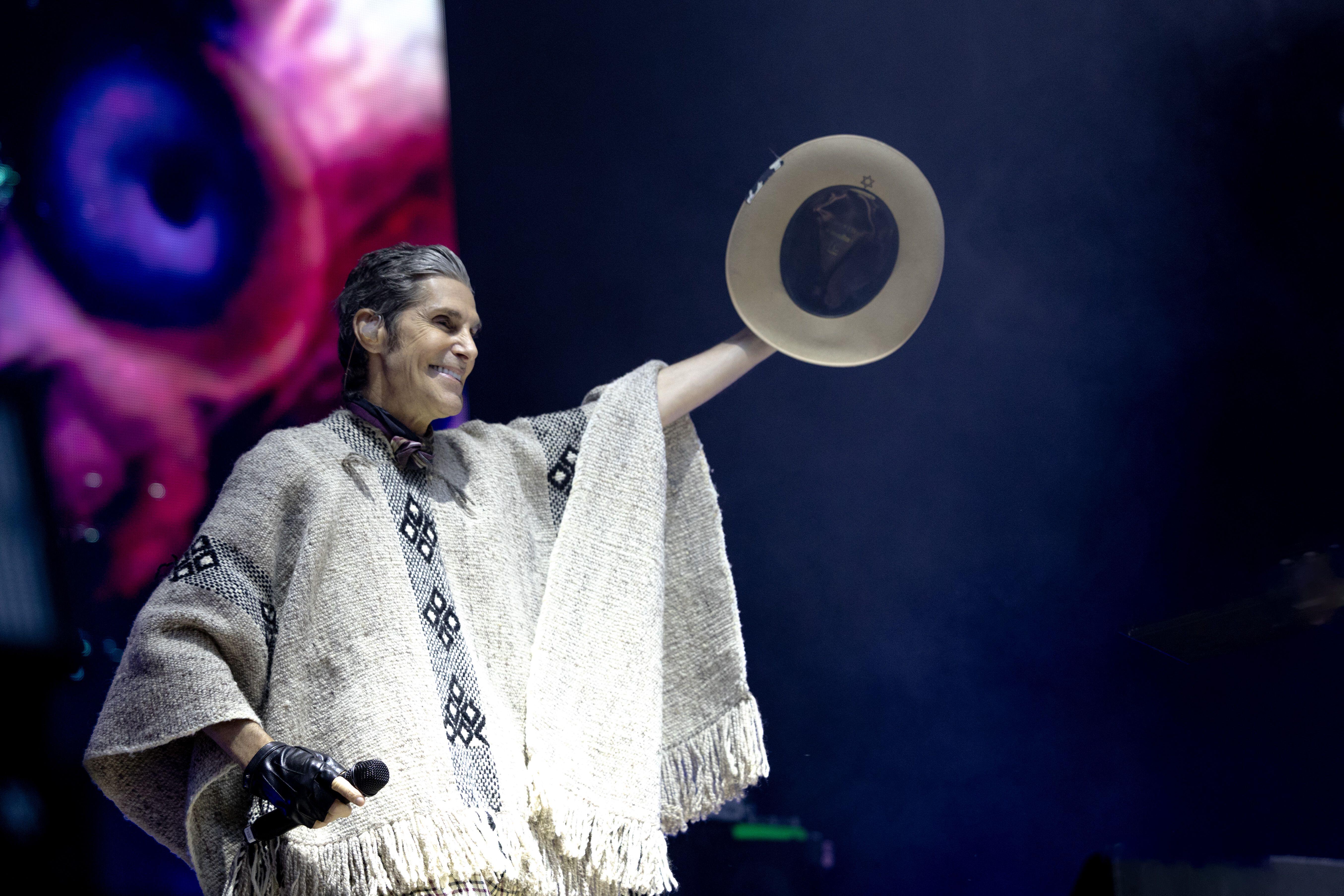 Perry Farrell raising his hat in his left hand while on stage