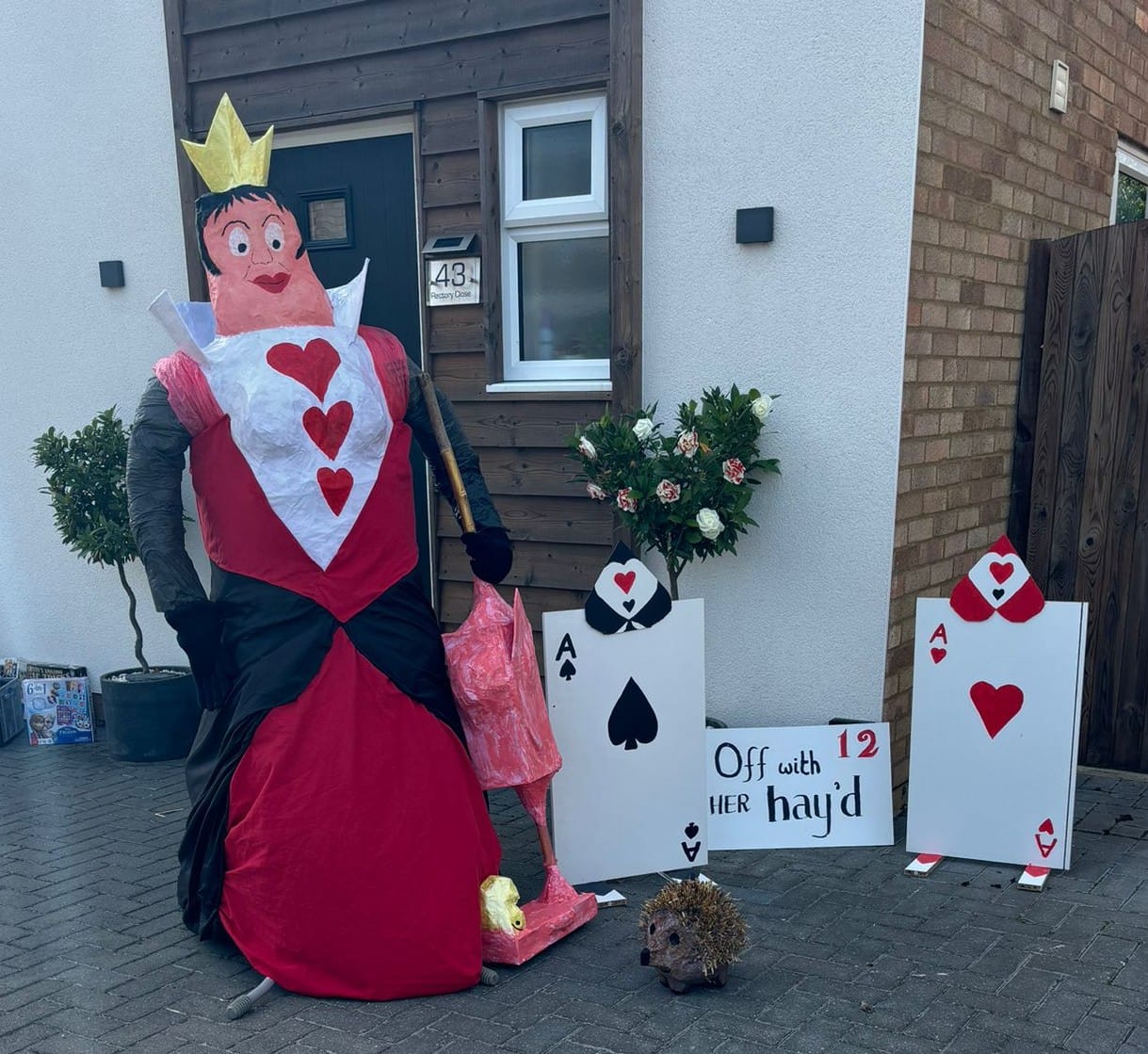 Scarecrow with crown on her head next to playing cards