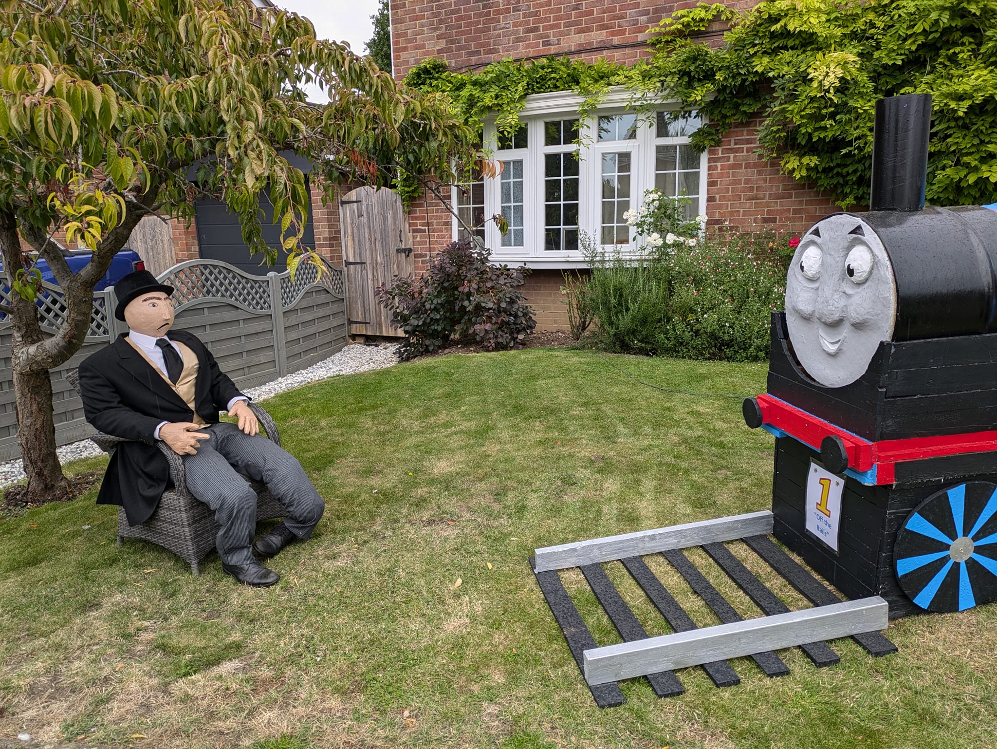 Scarecrow person in chair next to train