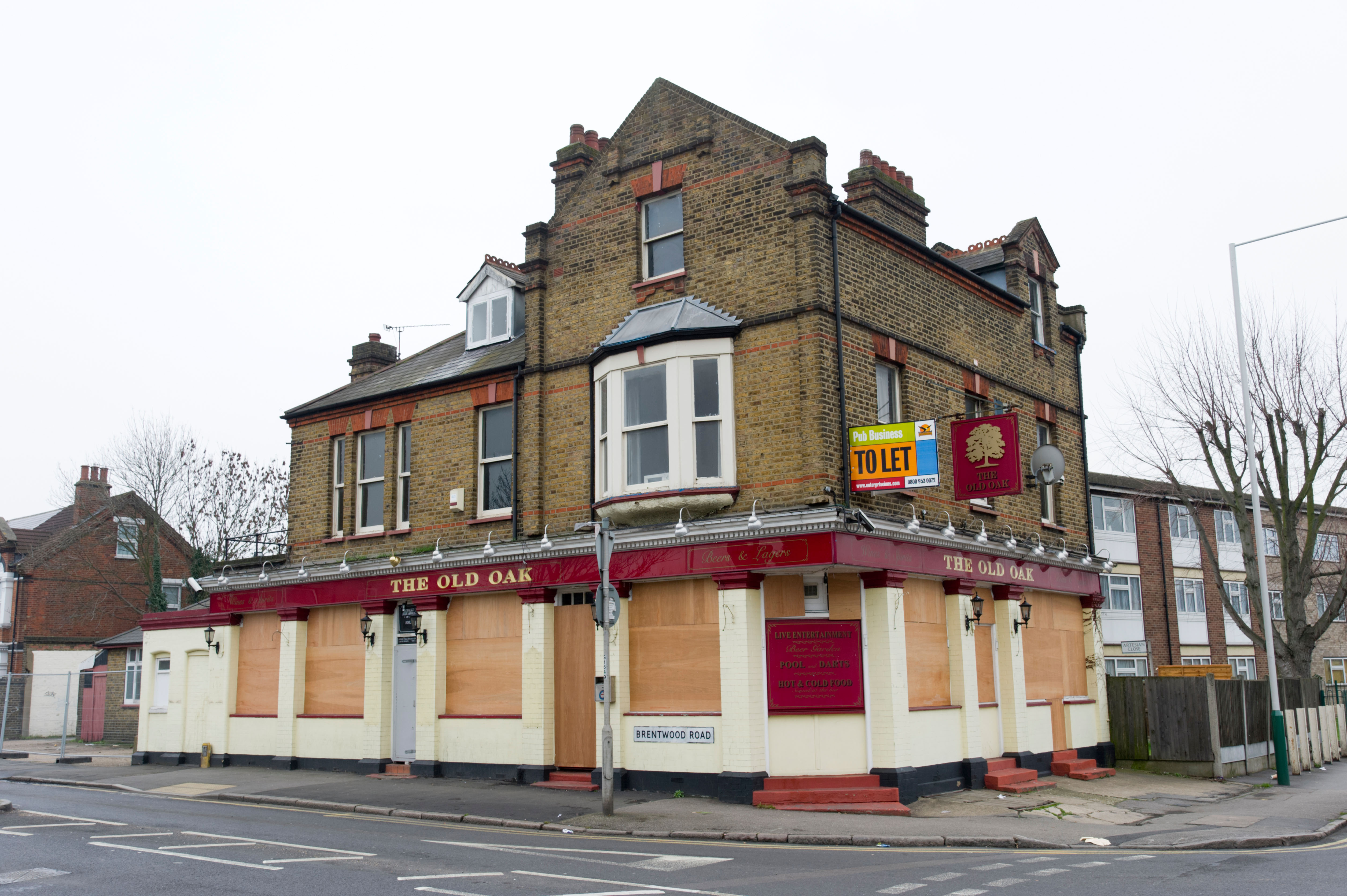 A boarded up pub with a 'to let' sign attached to it