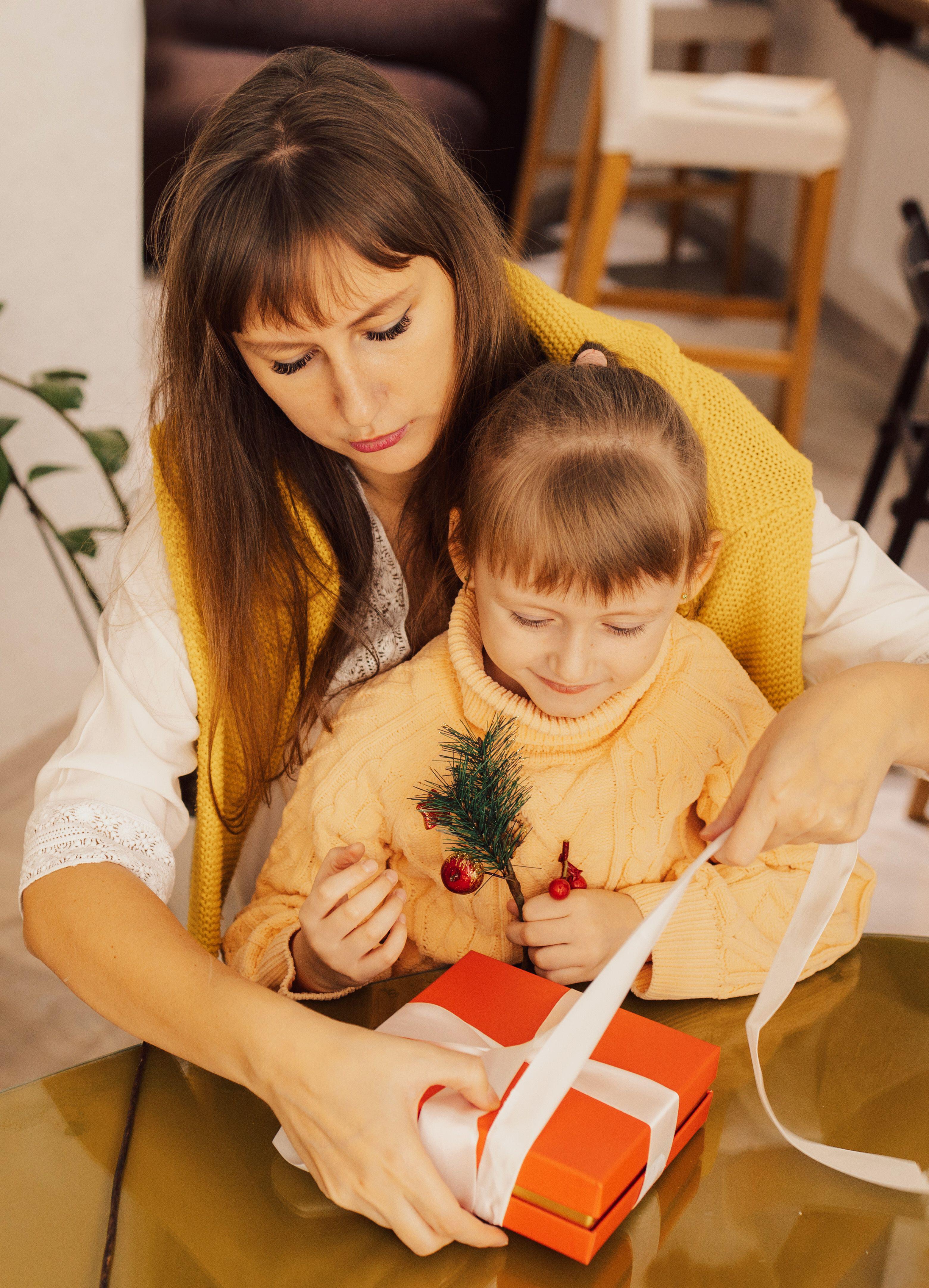 A mother helping a daughter wrap a Christmas present 