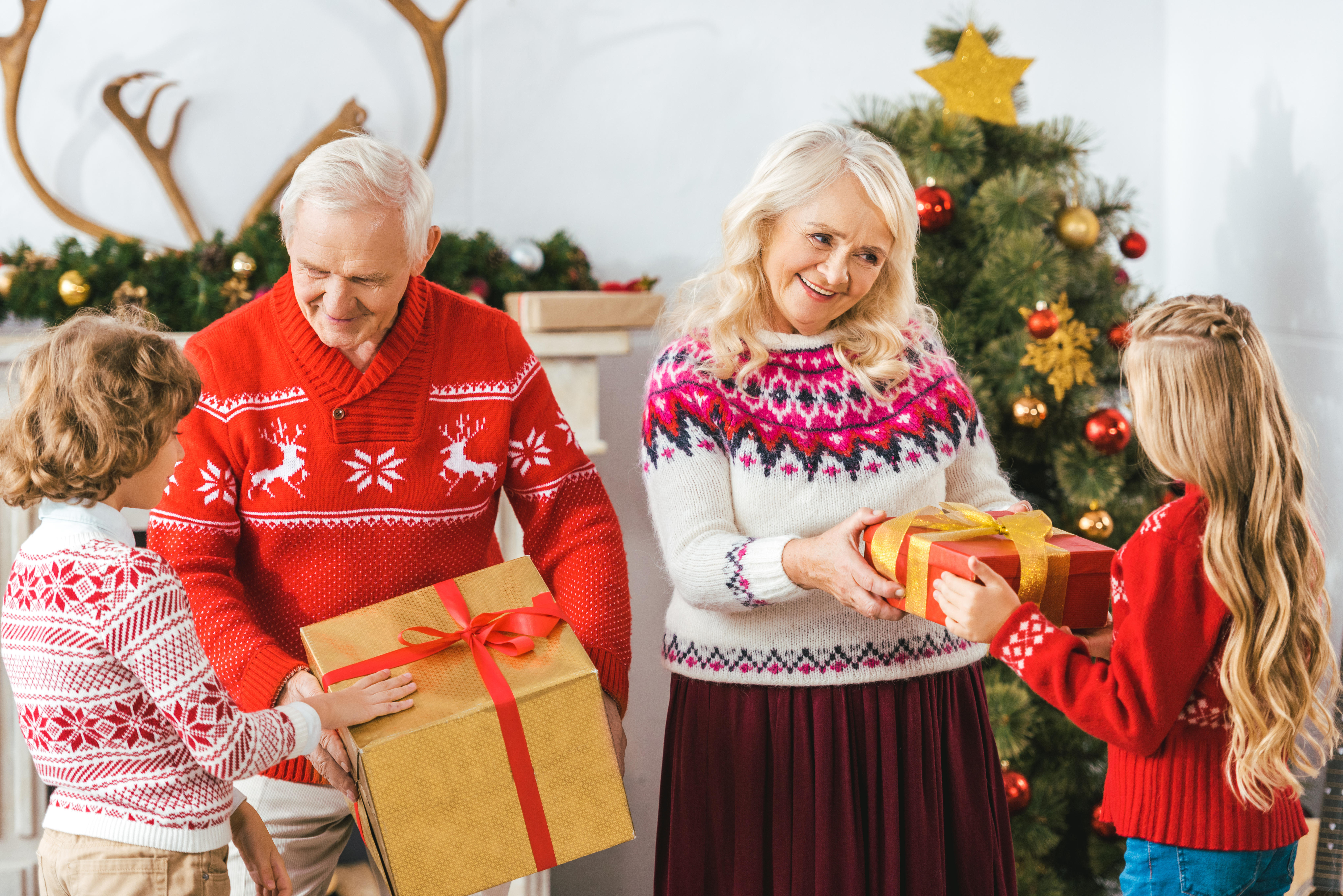 Grandparents handing their grandchildren presents at Christmas 