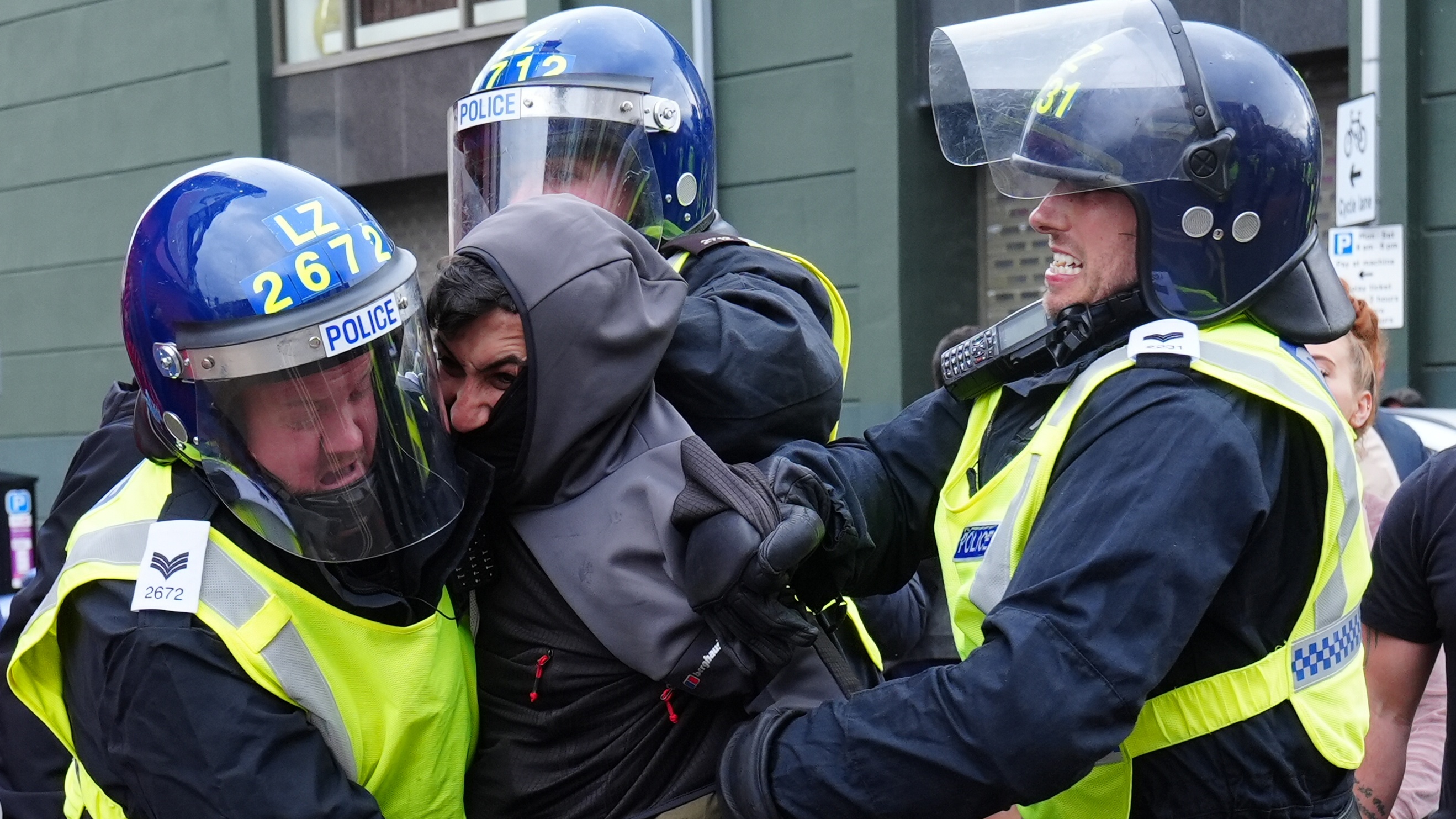 Three police officers in riot gear arrest a man during a riot in Middlesbrough