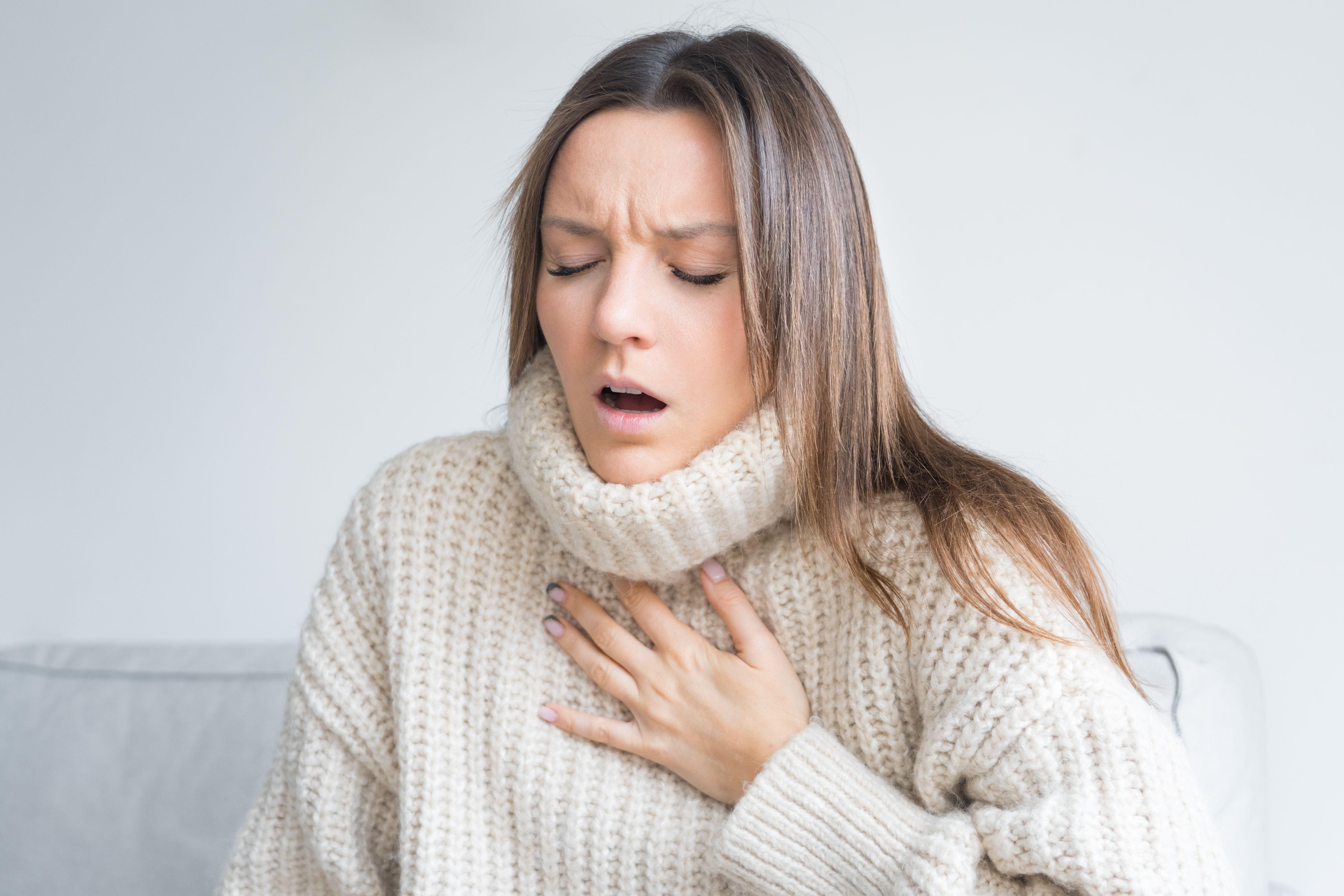 Woman, who is experiencing breath difficulties, gasping and putting her hand on her chest 