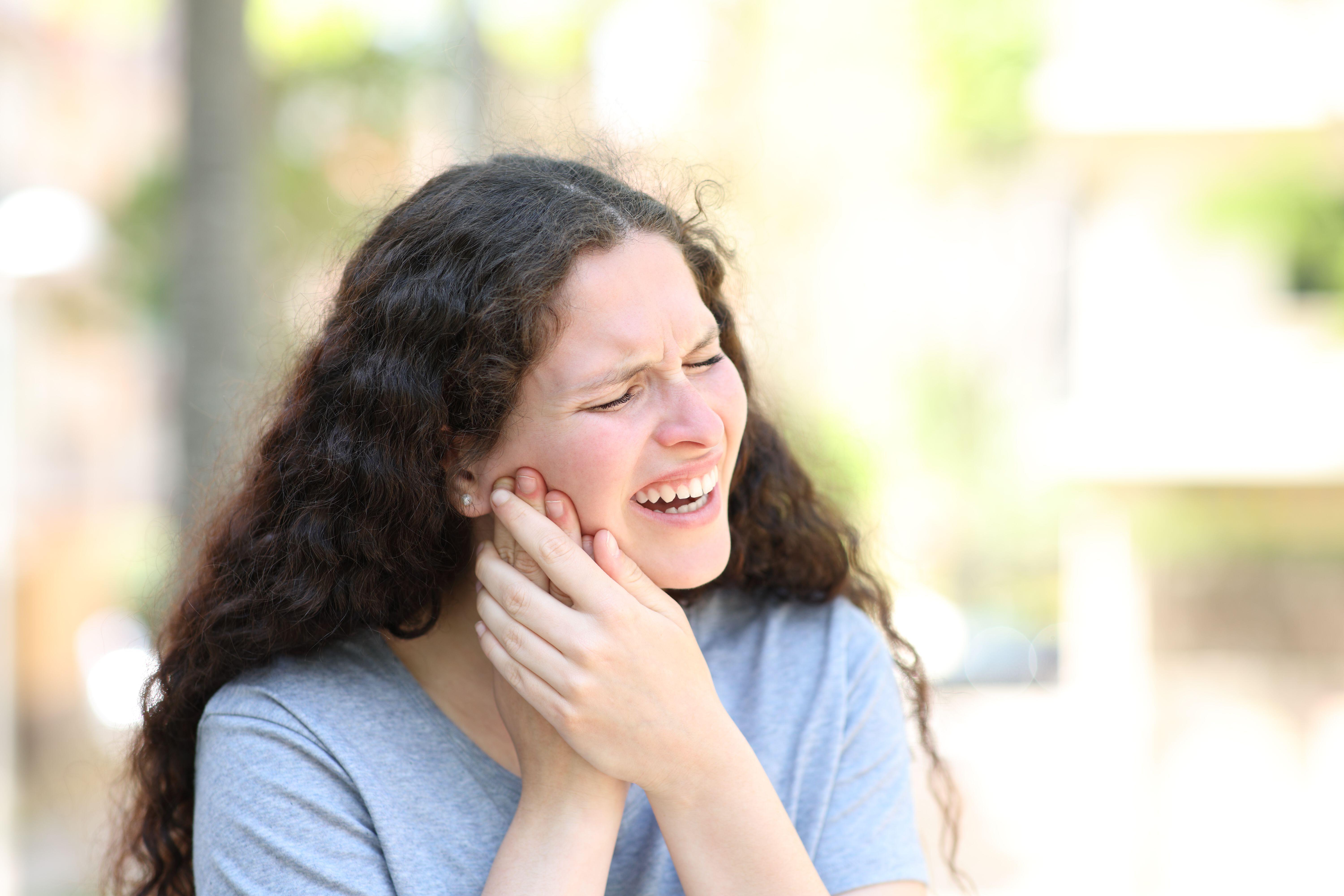 Woman suffering from jaw ache in the street 