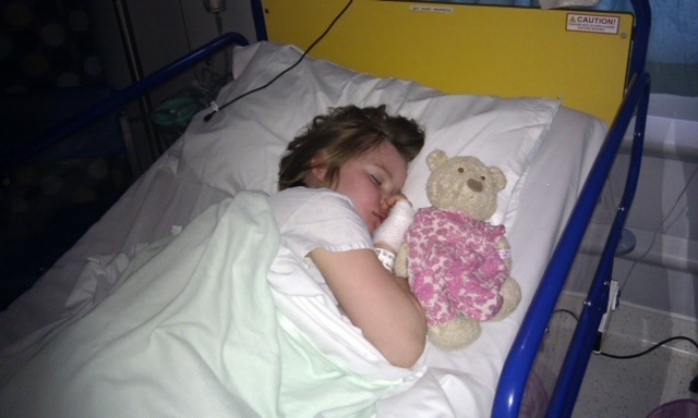 Jamilla Blake asleep in a hospital bed with a Teddy bear