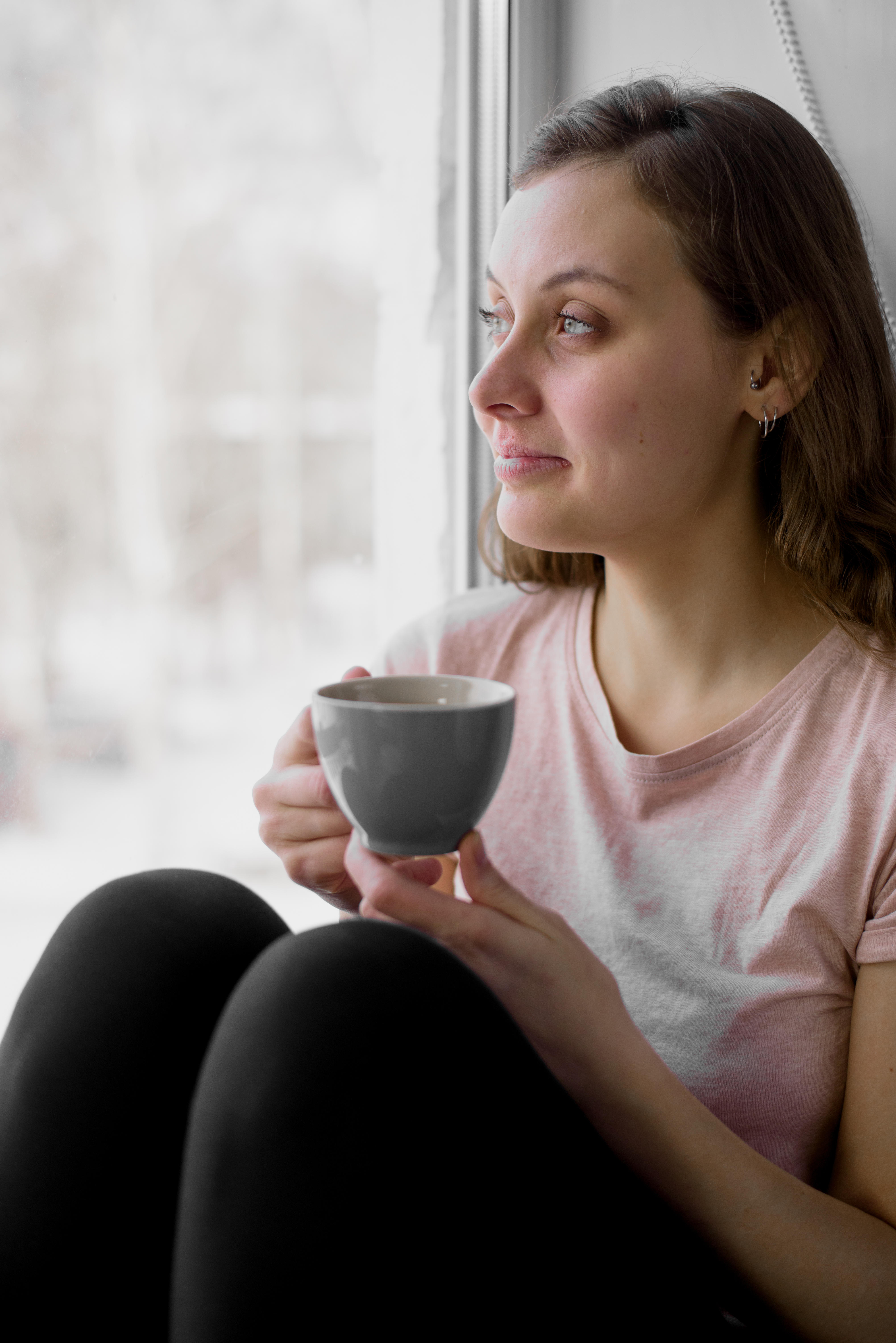 Woman sat on a windowsill drinking tea