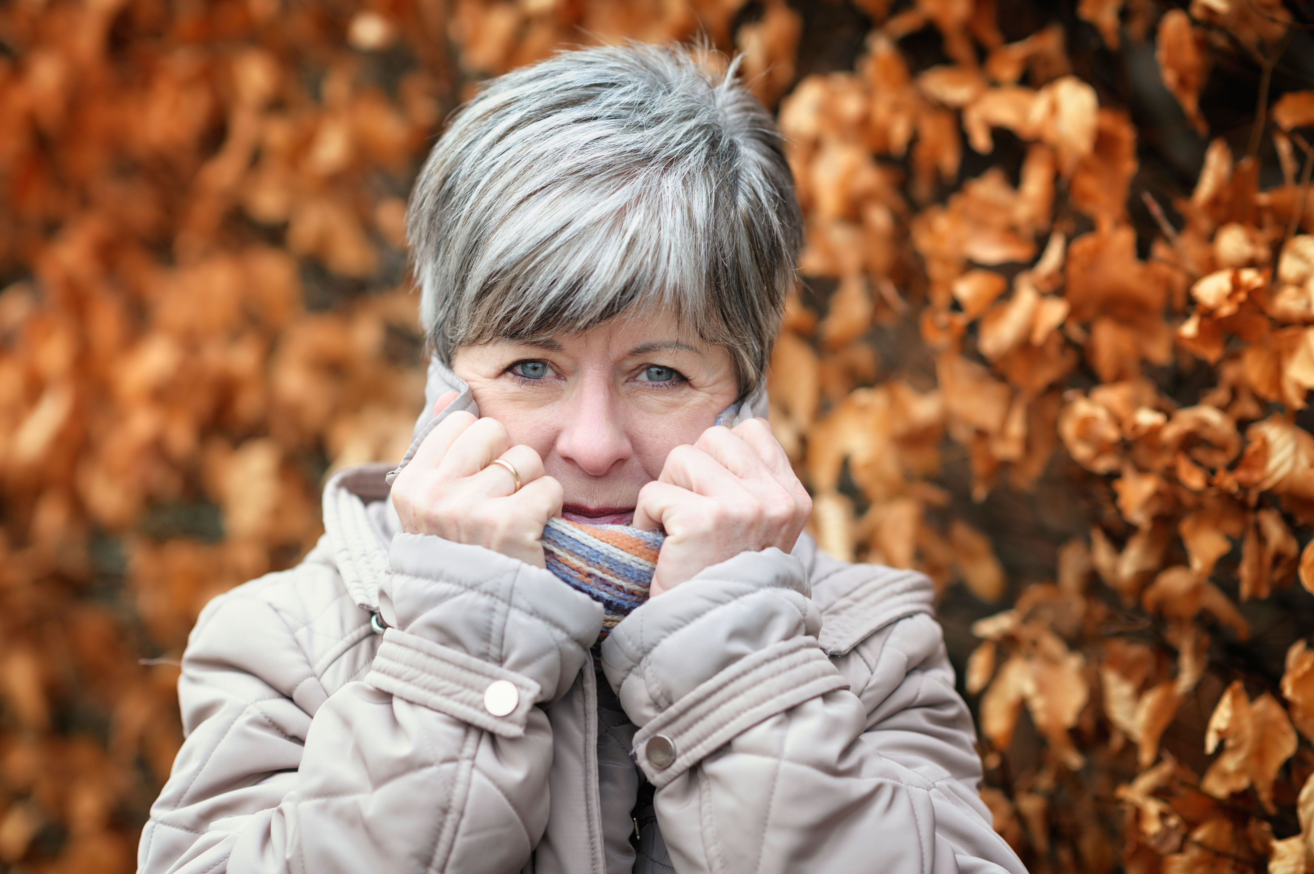 Shivering senior woman pulling up the collar of her coat