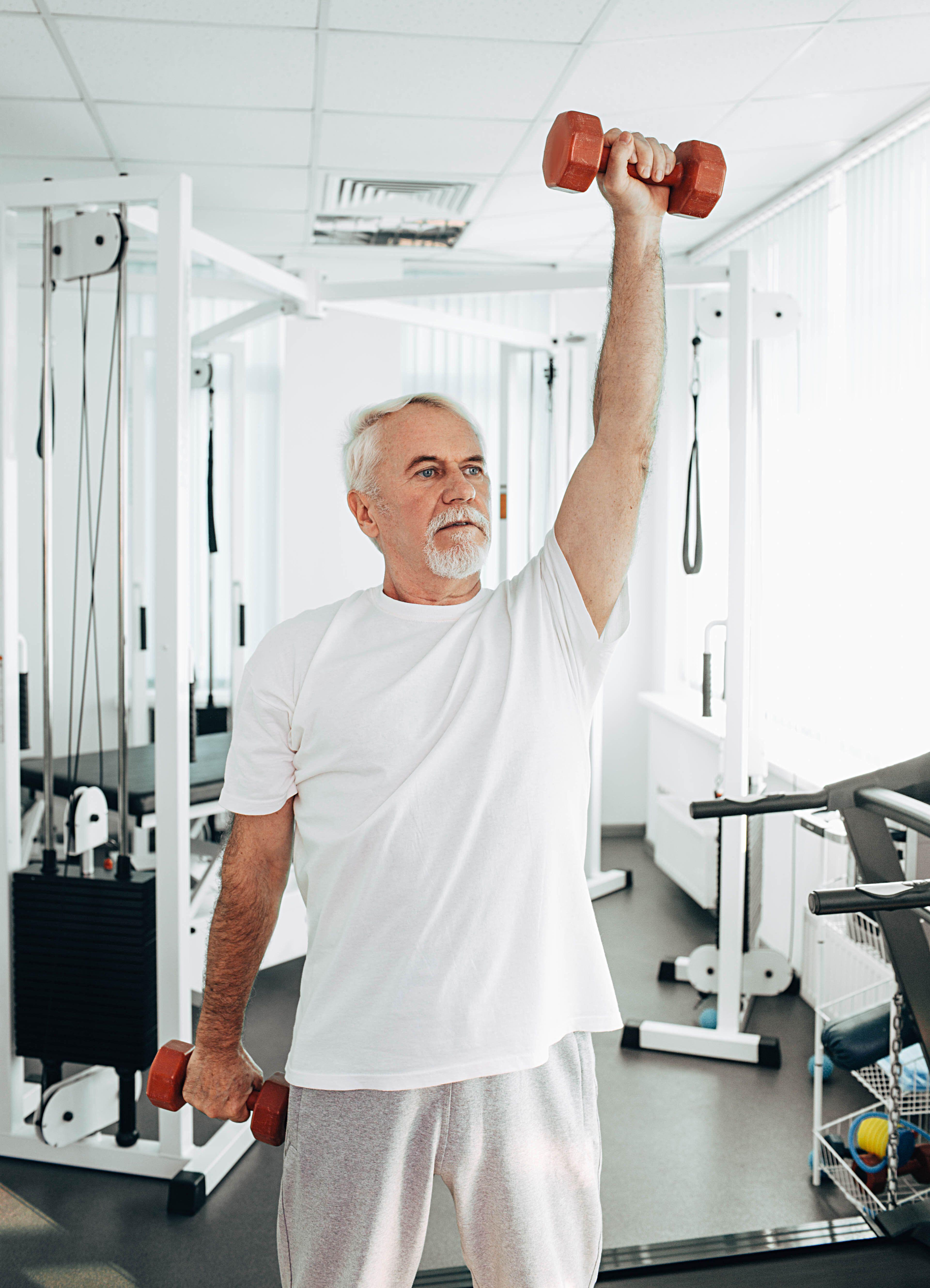 Senior man lifting weights at a gym 