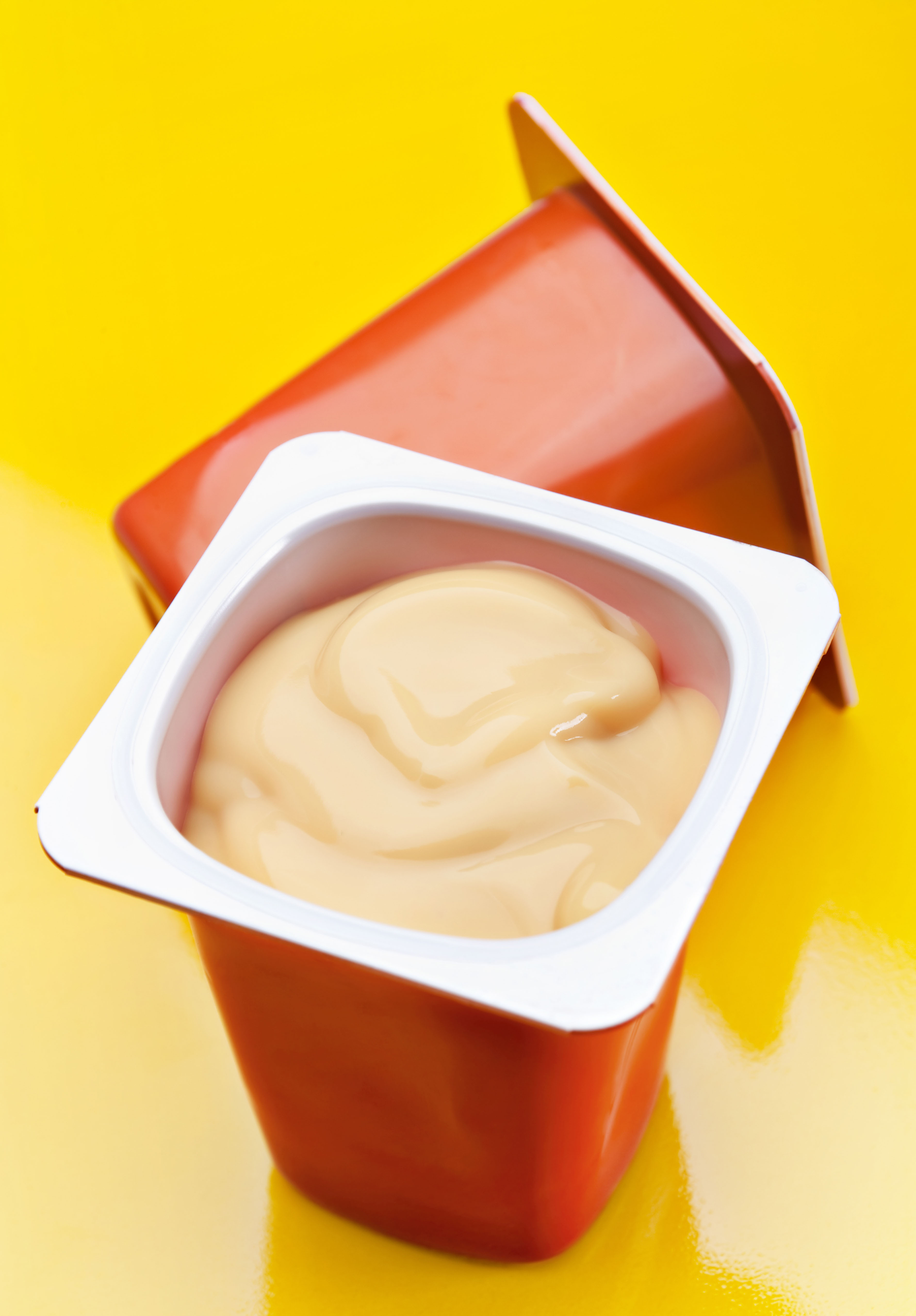 Cream caramel yoghurt in plastic box on yellow