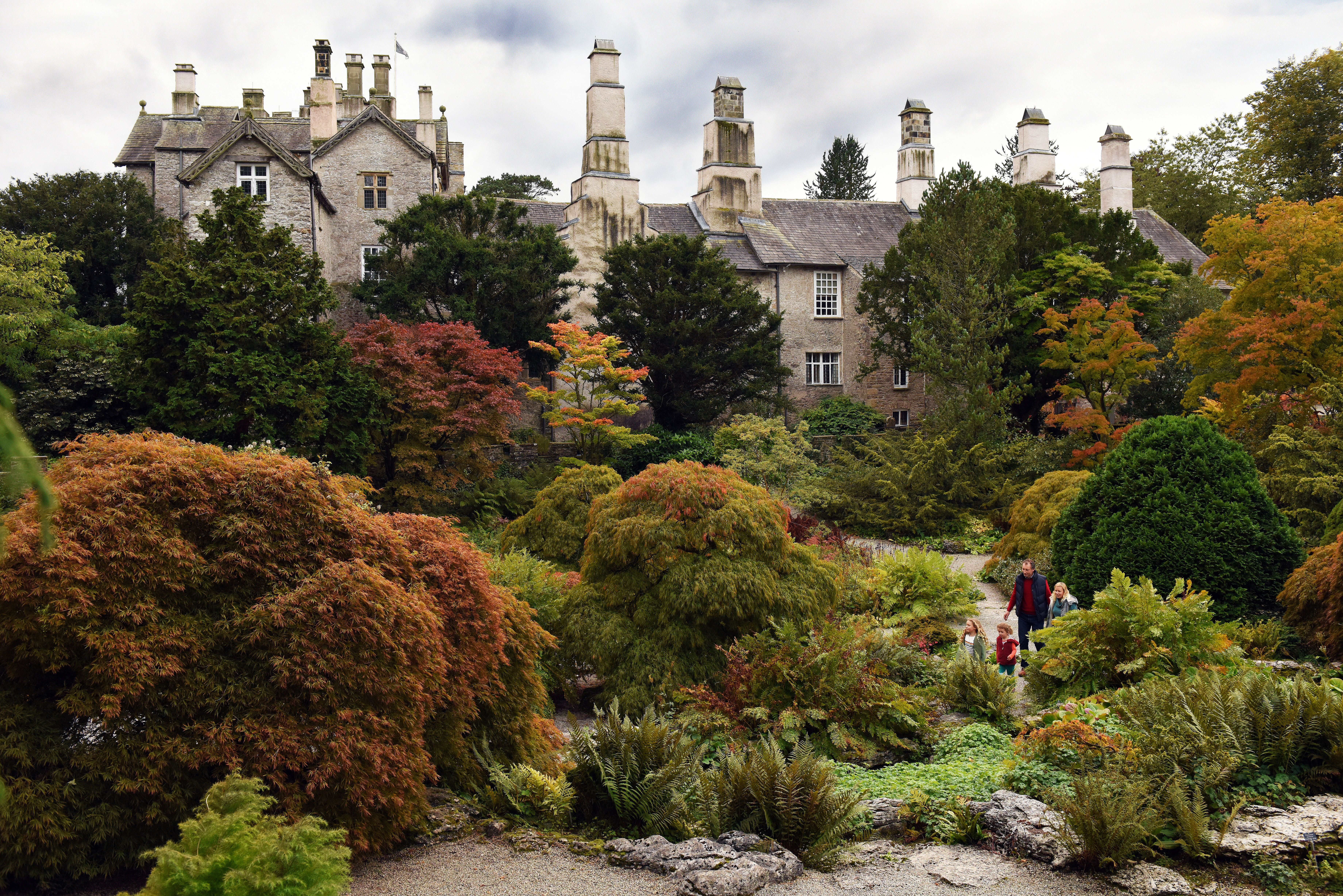 Autumnal trees in front of a large grey-stone house