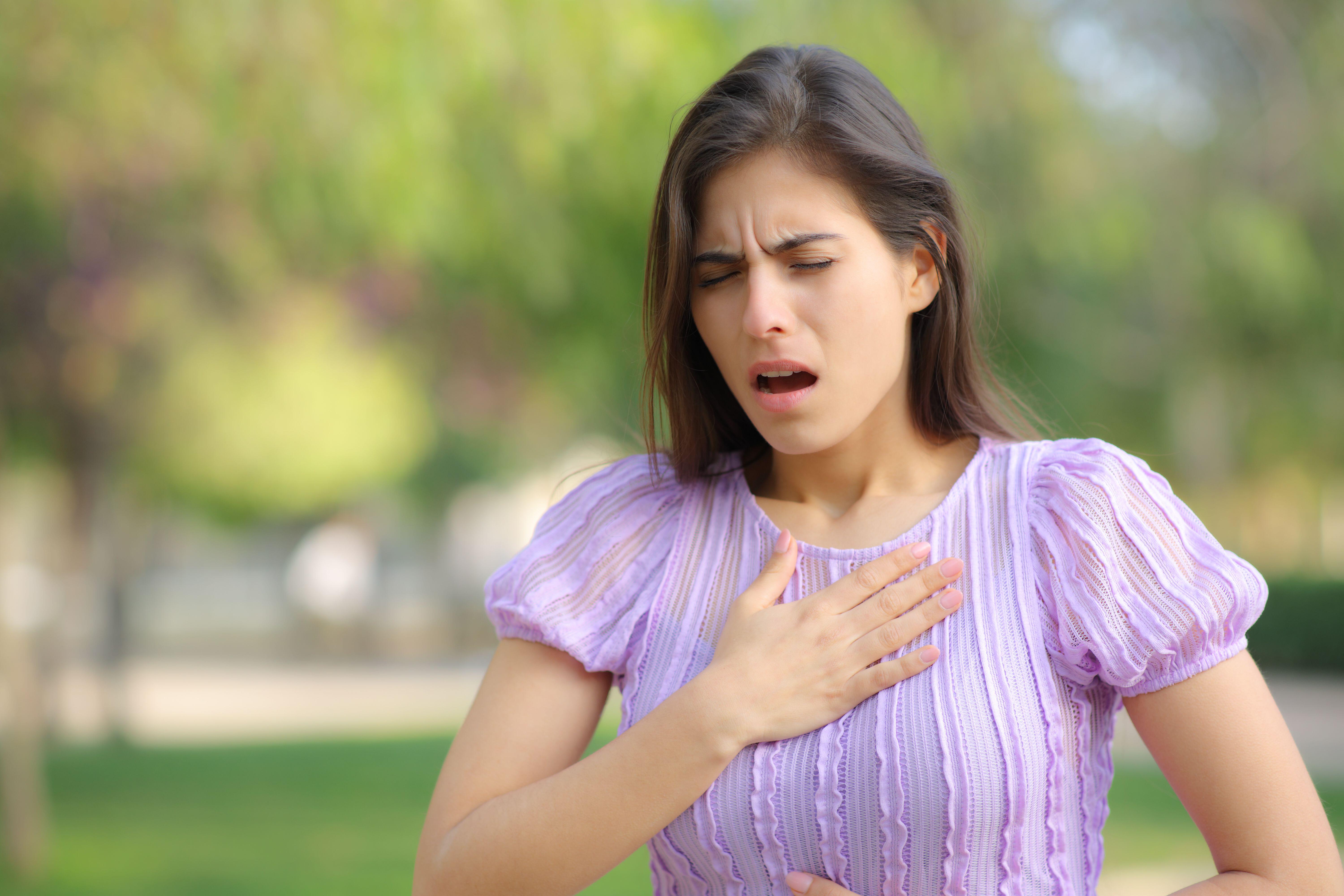 Stressed woman suffering from an asthma attack in a park