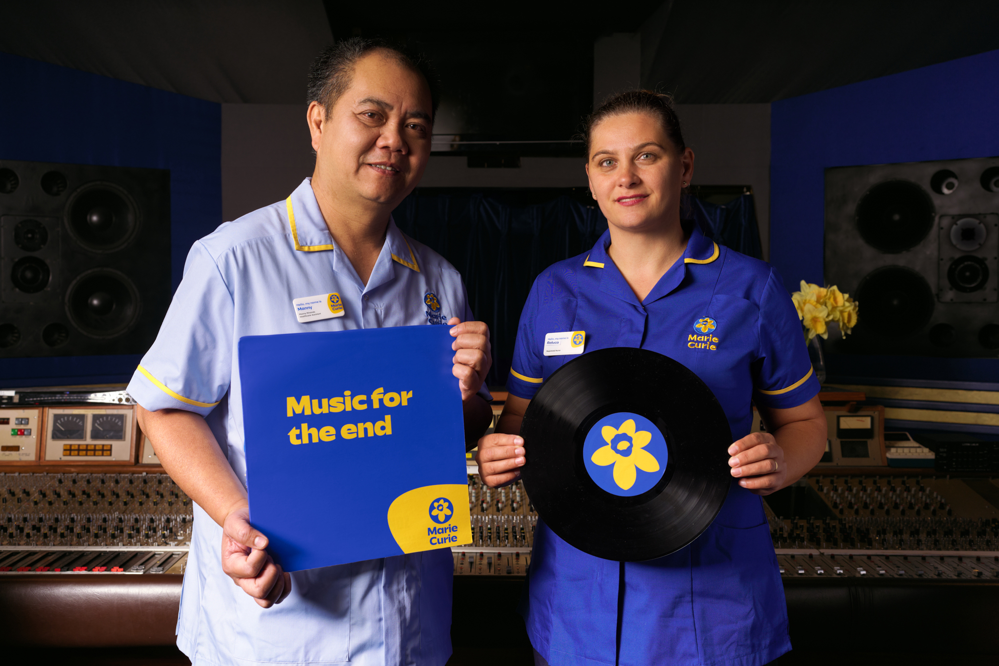 Two health workers stand next to each other holding a music record and cover 