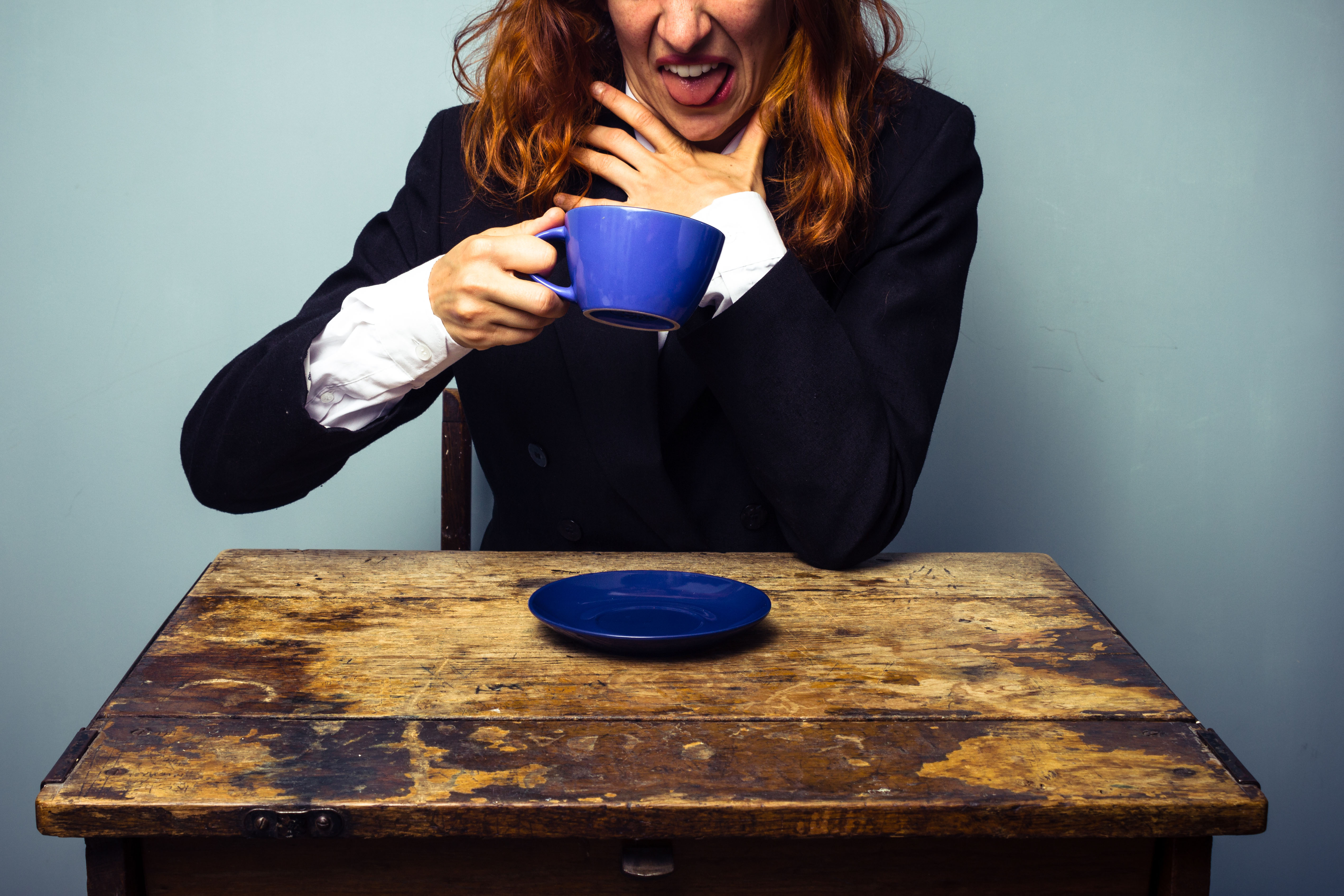 Young business woman pulling faces after drinking a bad cup of coffee