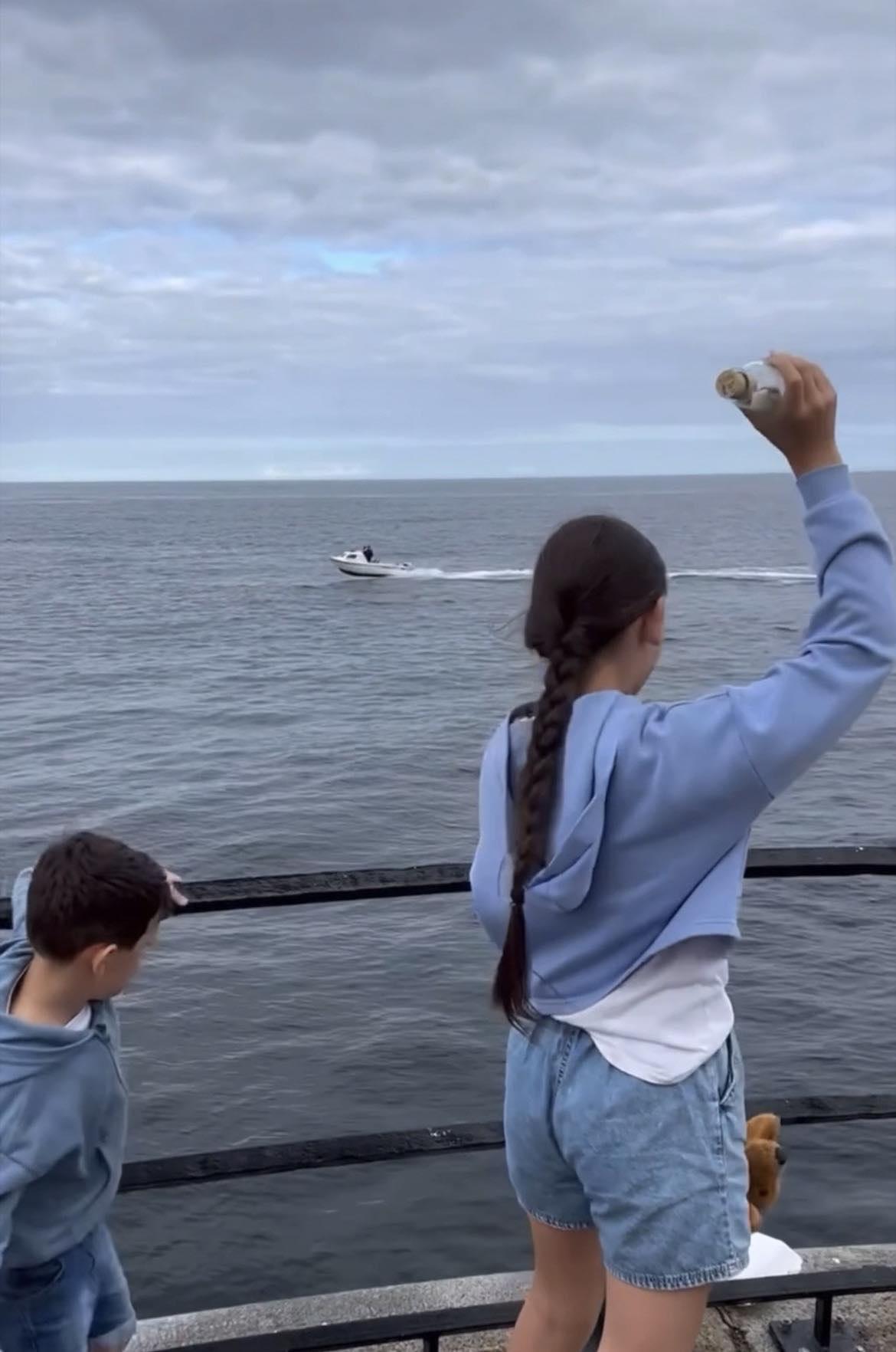 Girl throwing bottle into water 