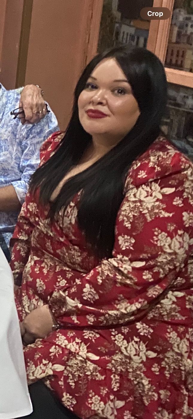 Woman wearing a red dress whilst sat at a table