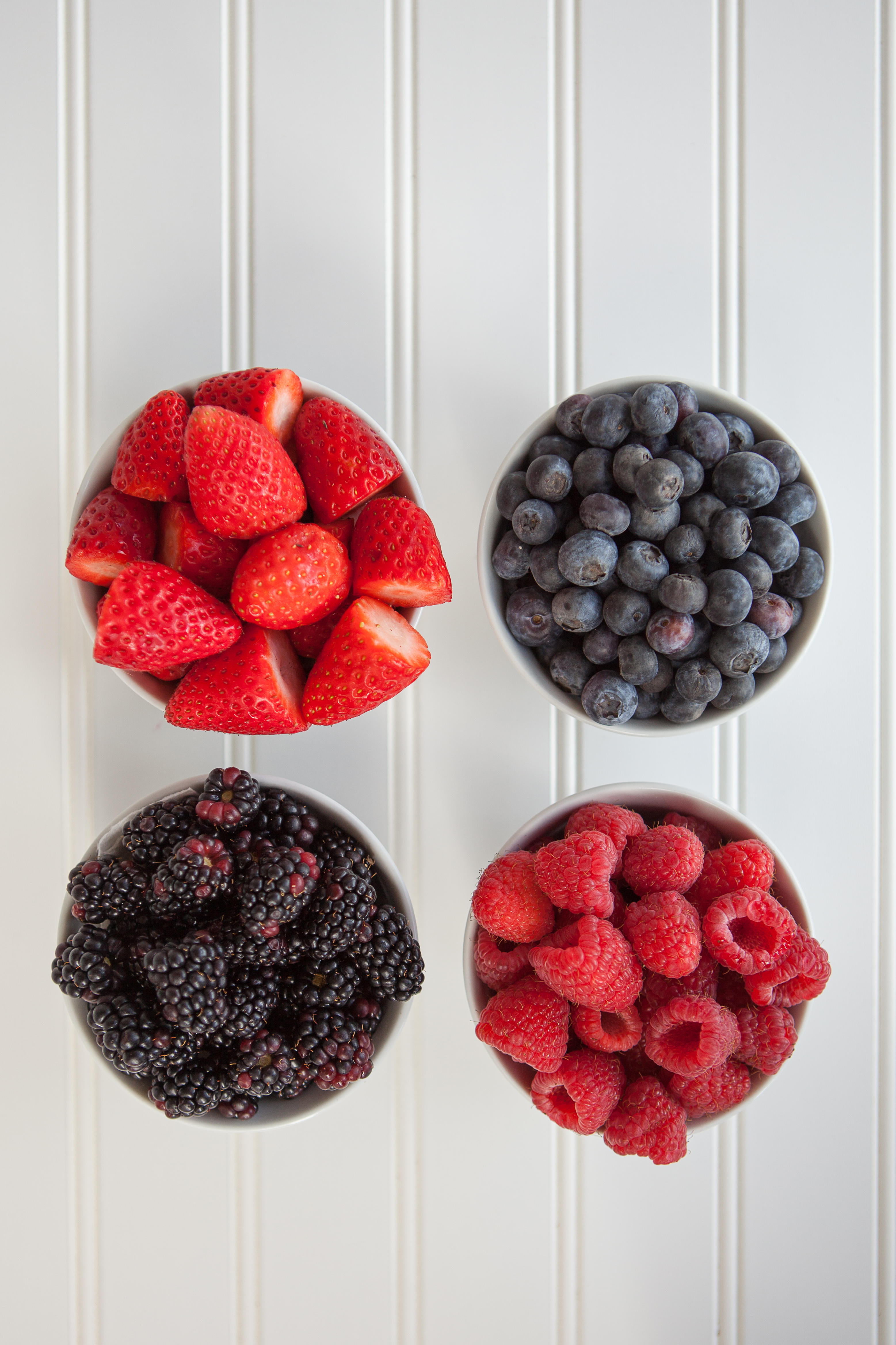 One bowl of raspberries, one bowl of strawberries, one bowl of blueberries and one bowl of blackberries