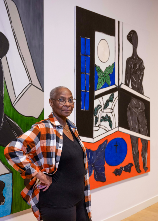 Everlyn Nicodemus standing in front of one of her paintings