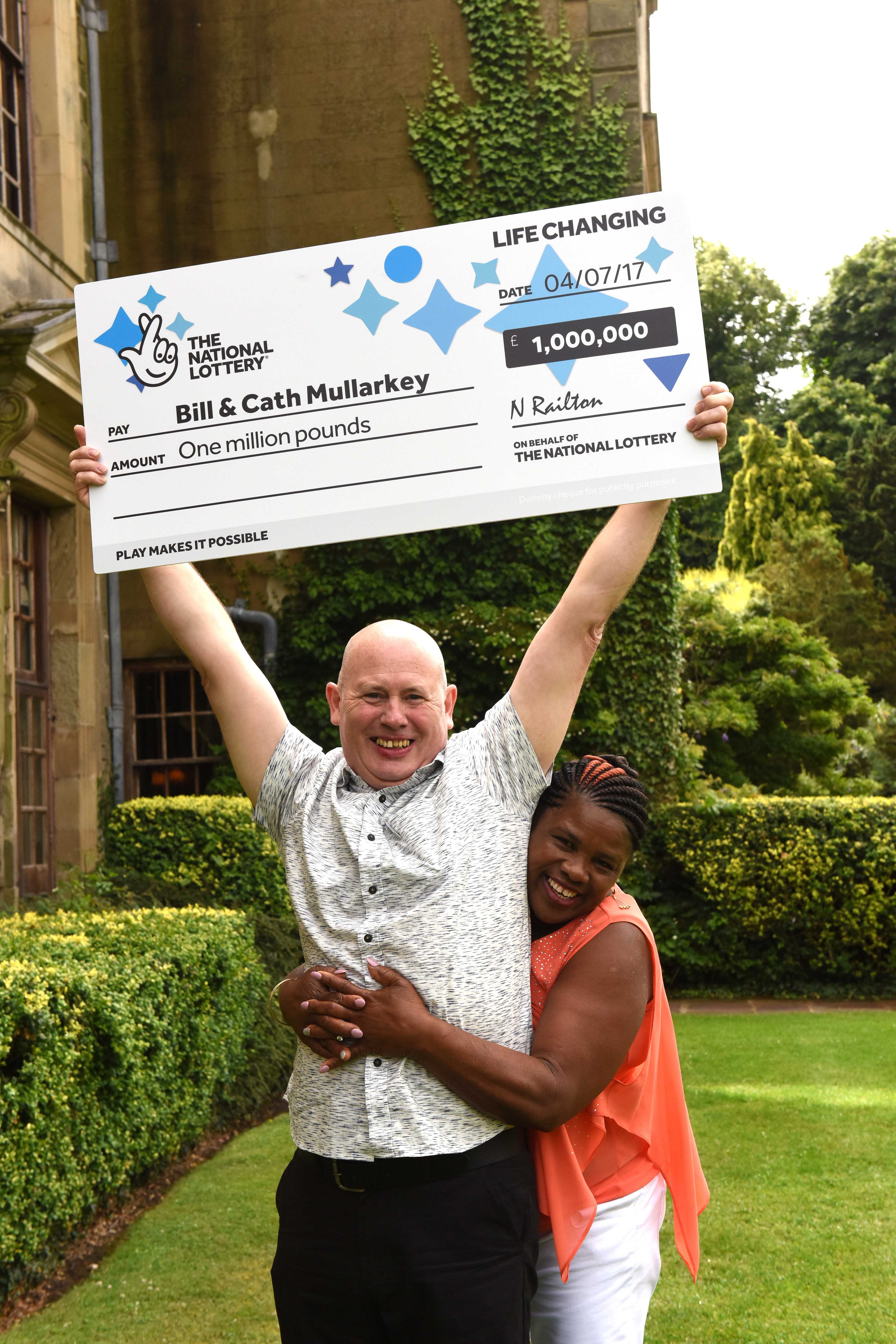 Two people hold a giant cheque