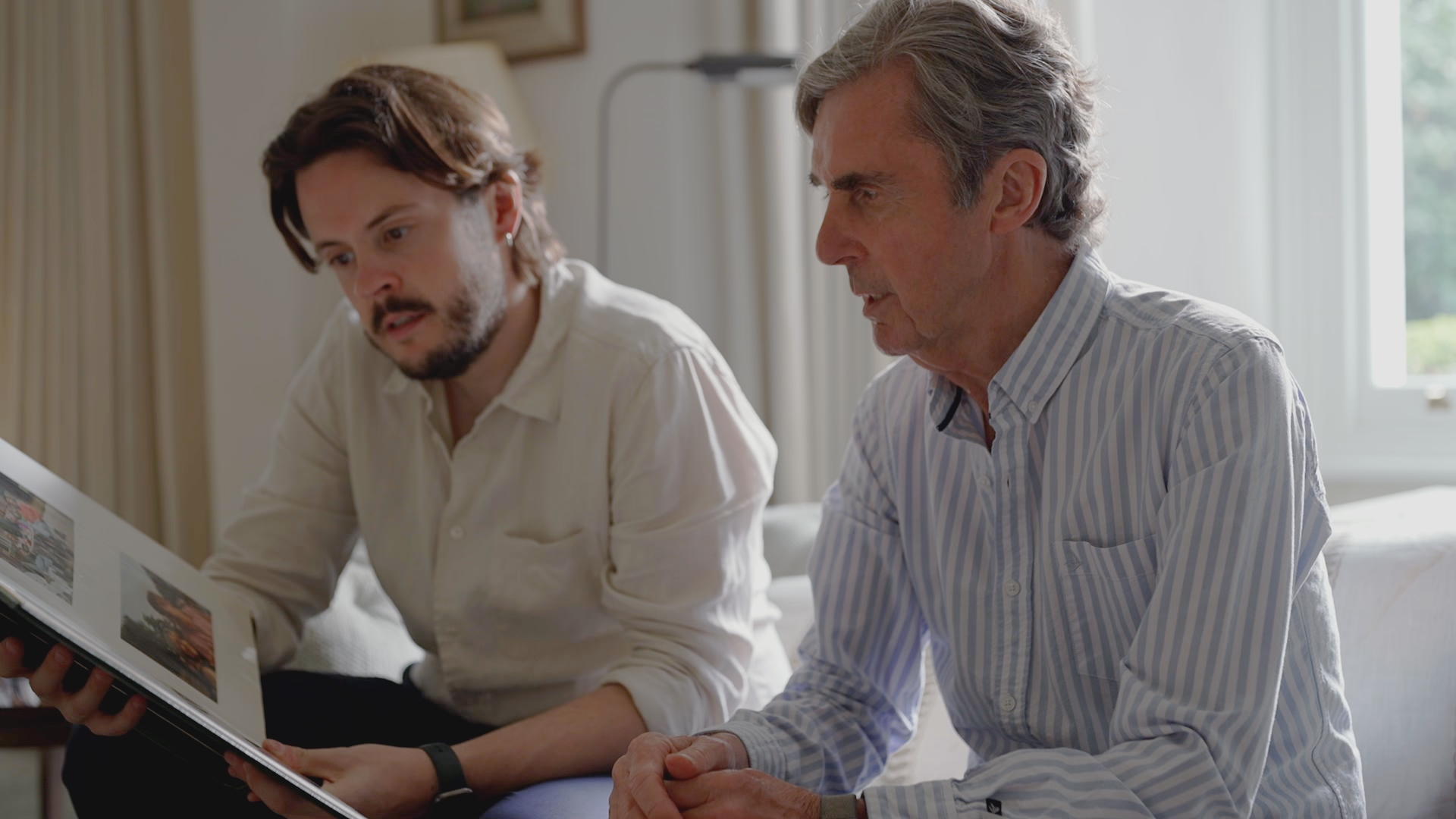 John Stapleton and his son Nick looking at a family photo album